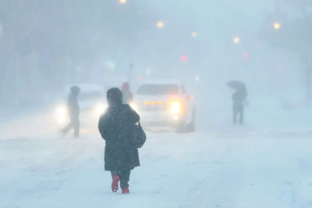 A person in a coat walking in a blizzard.