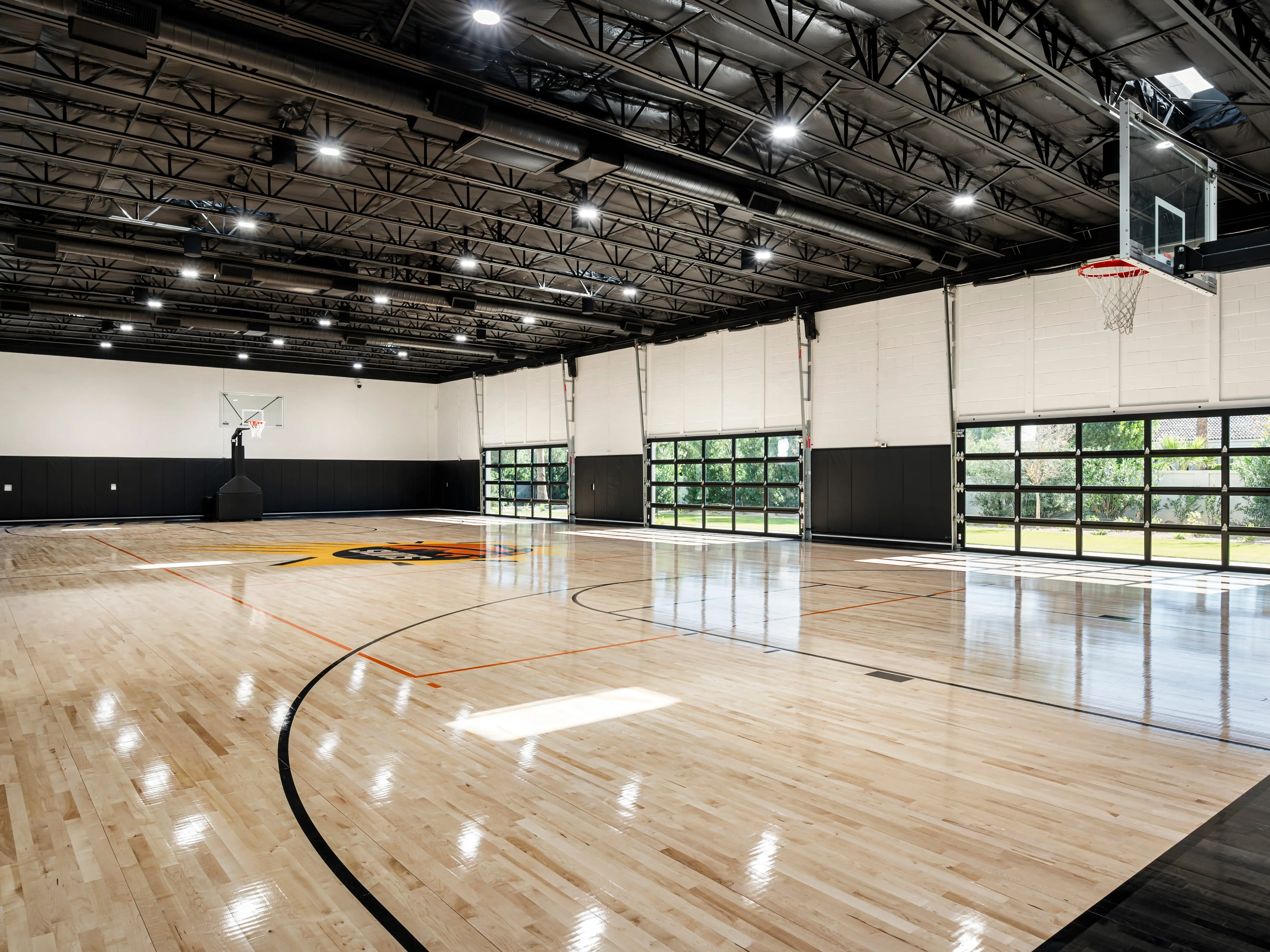 A basketball court with large garage doors on the side.