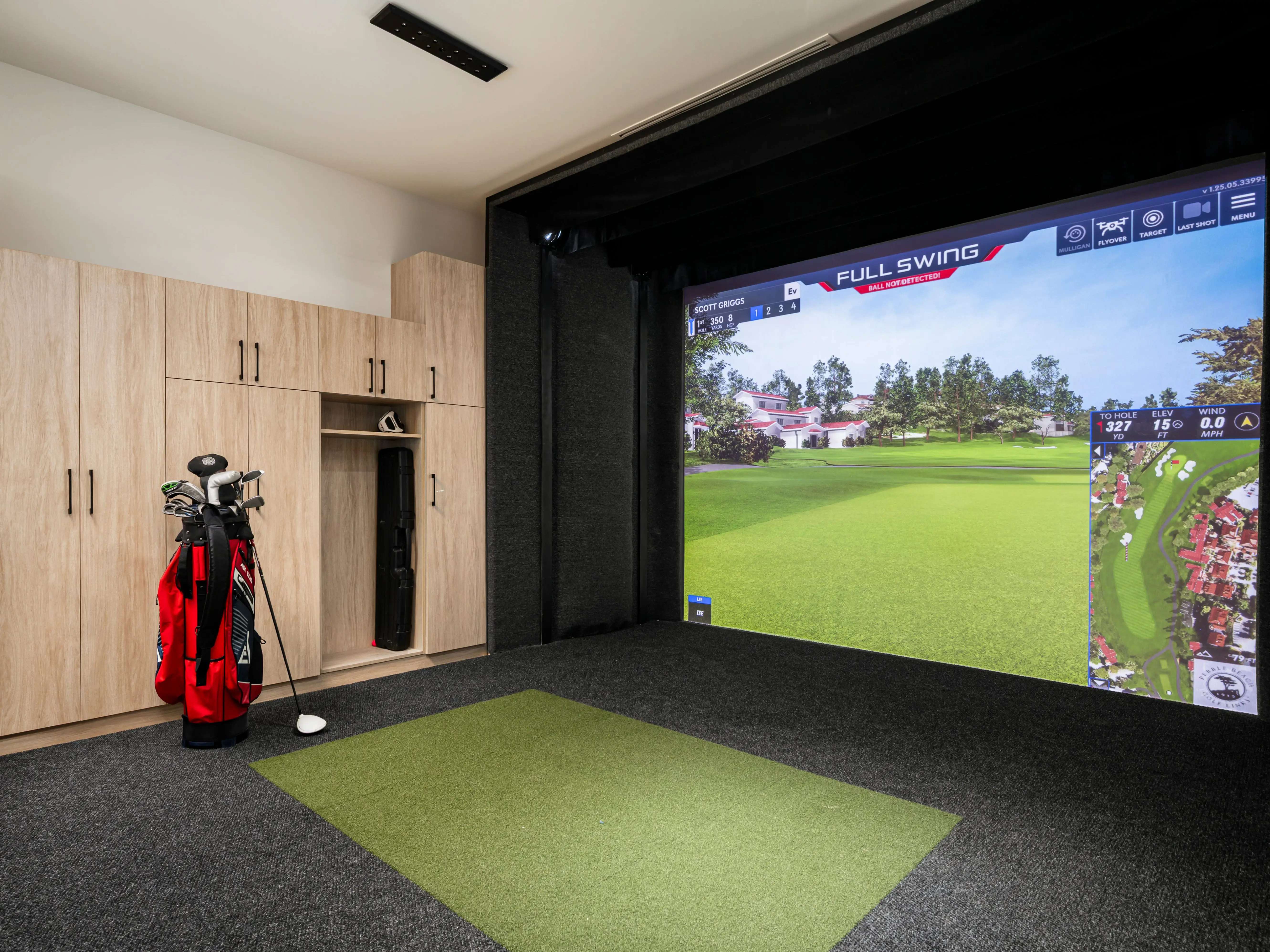 A bag of golf clubs next to a golf simulator.