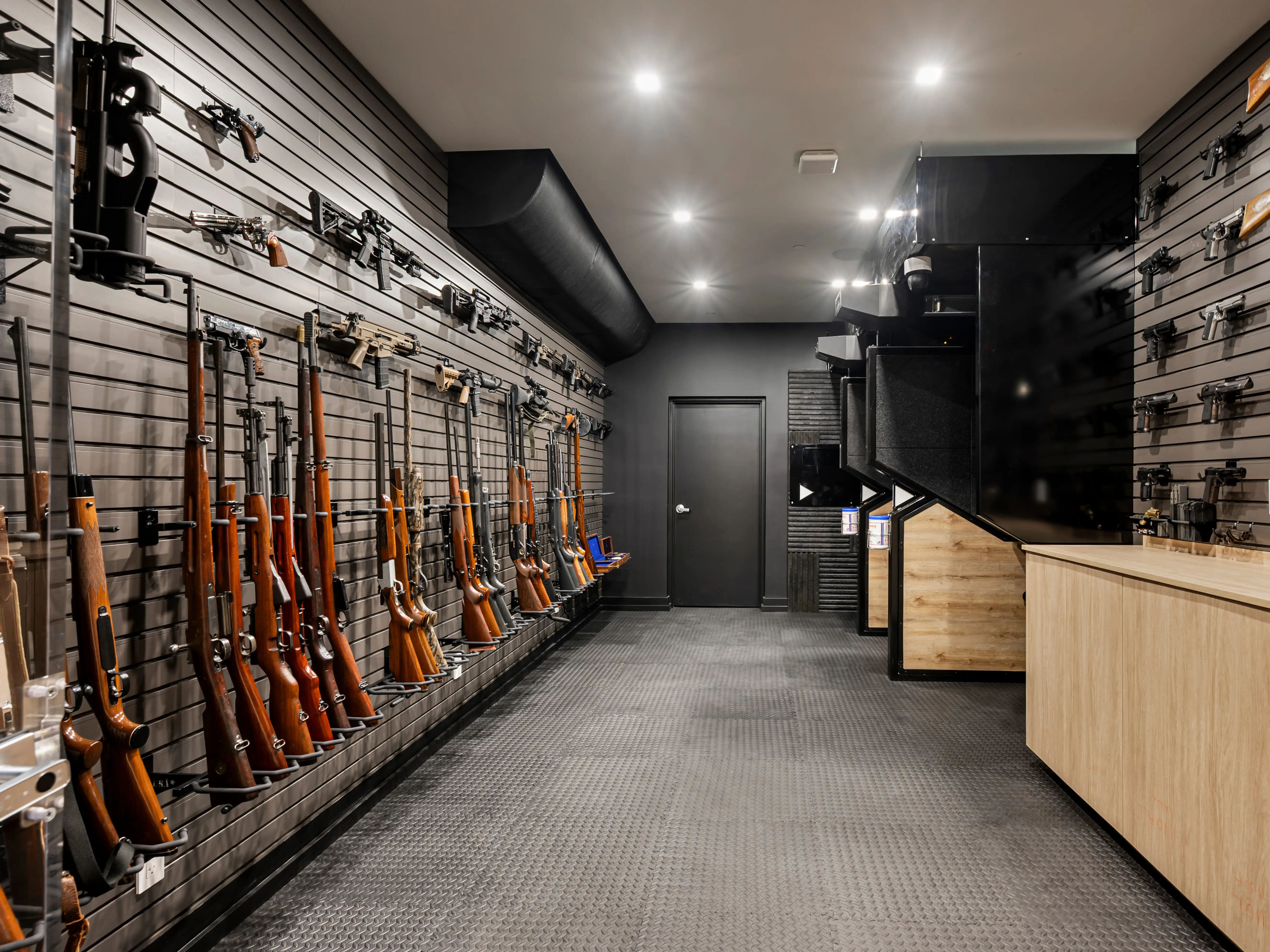 Guns lining the walls of a room in front of a shooting range.