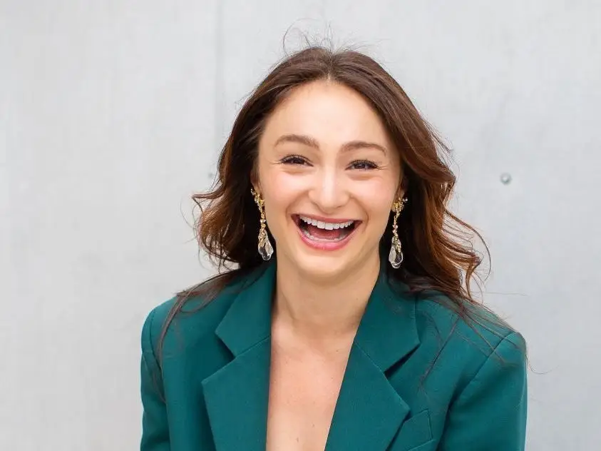 a woman smiling in a dark green blazer