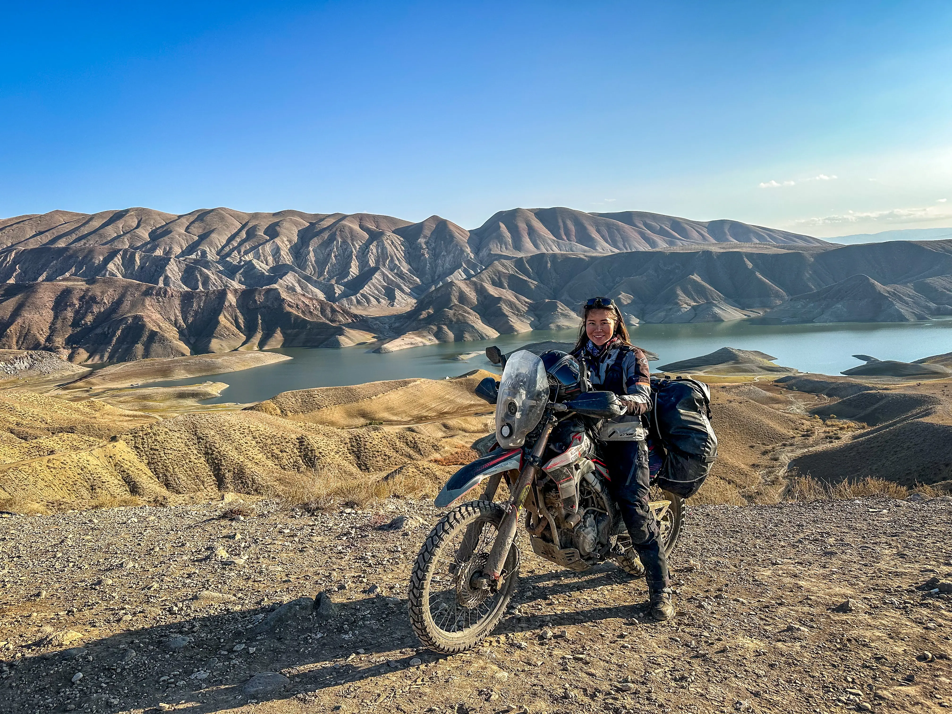 a woman on a motorbike poses on a mountain