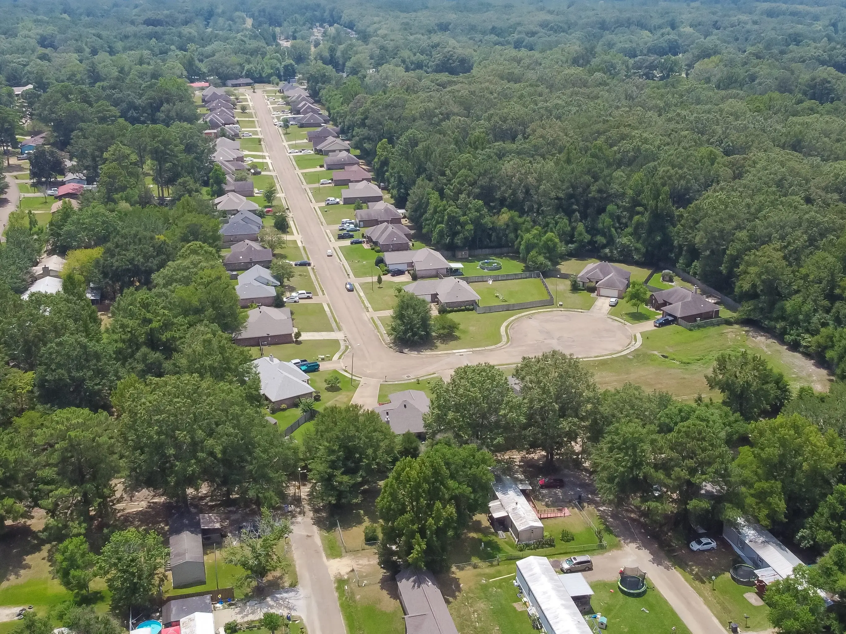 New development single family houses near row of manufactured, modular, and mobile homes in Richland, Rankin County, Mississippi suburb Jackson, USA lush green trees. Aerial view affordable housing
