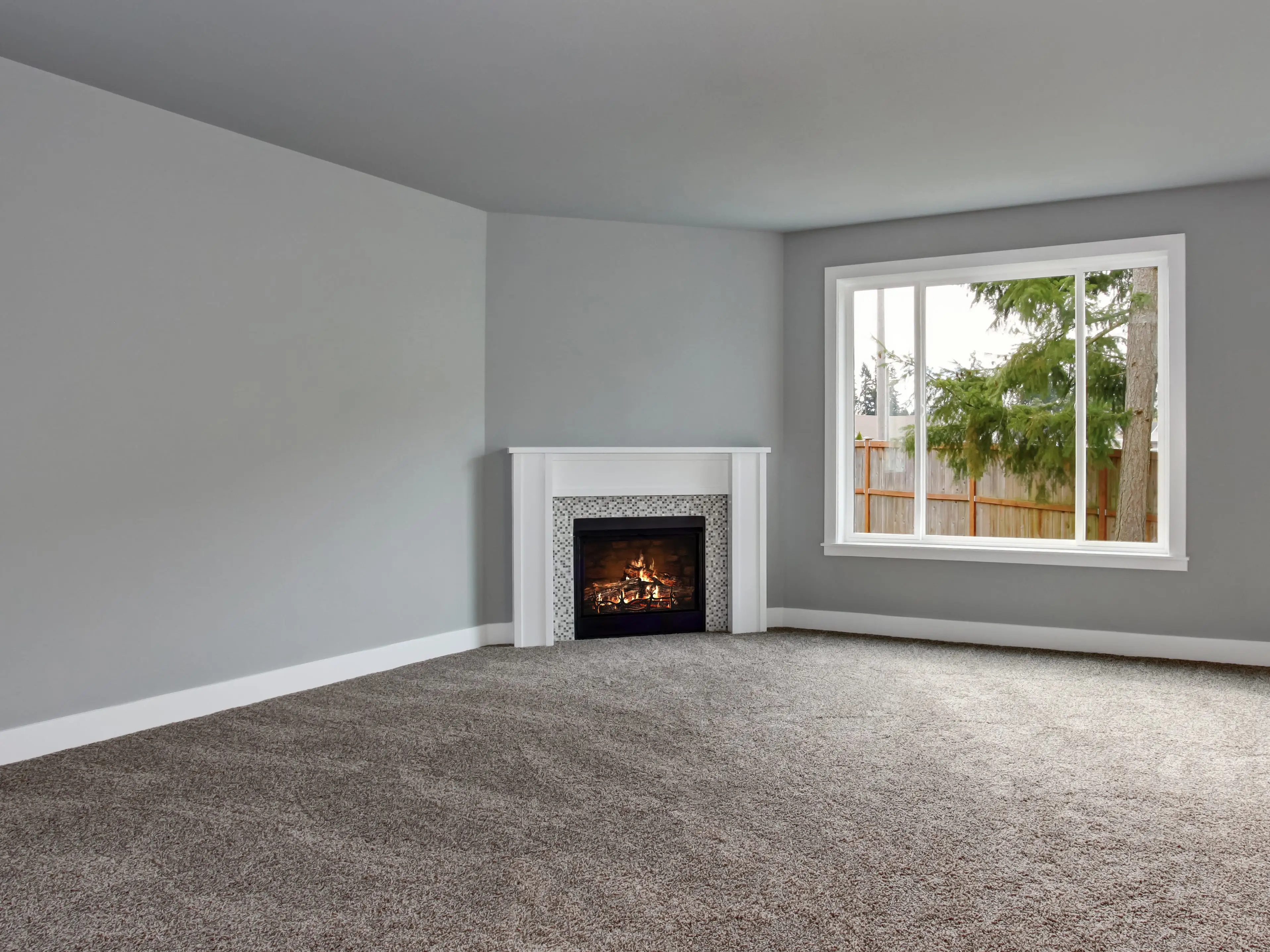 Room with corner fireplace, wall-to-wall gray carpet