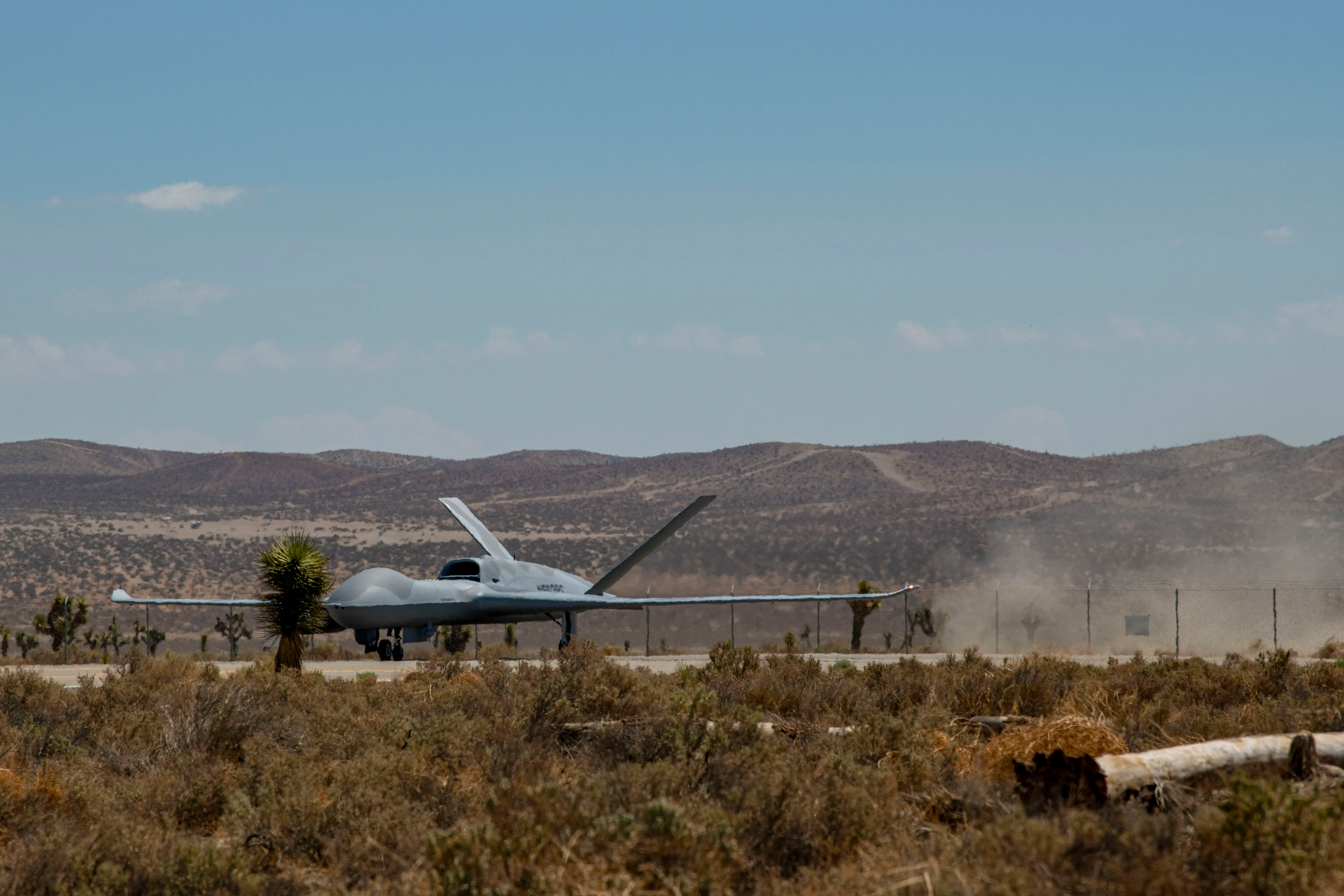 A large, grey aircraft sits on a runway in the desert.