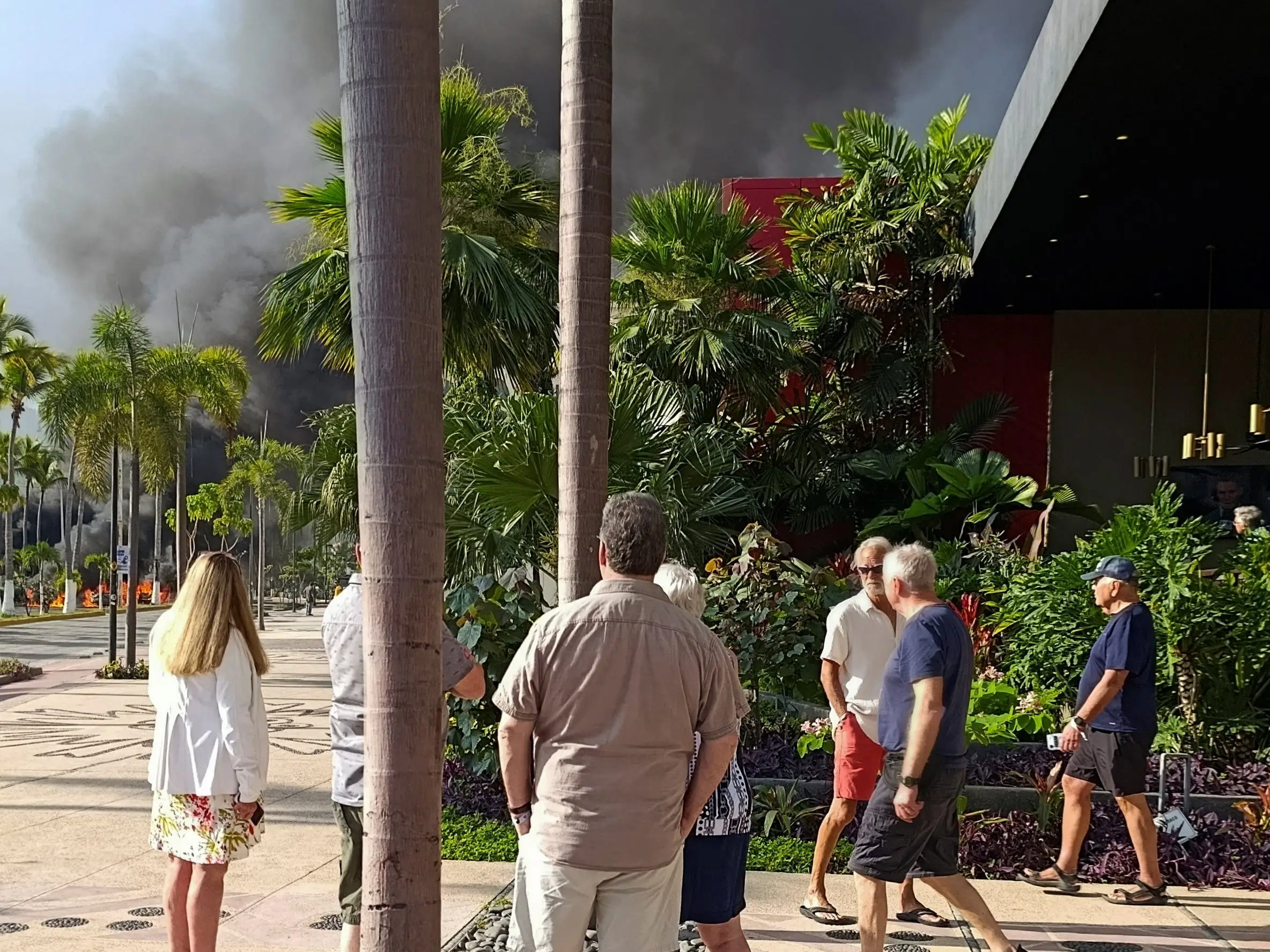 Tourists watch a column of smoke