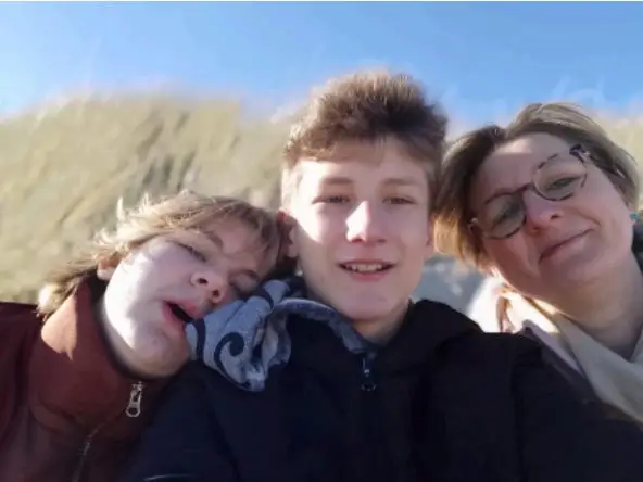 Mother with two children and grass in the background.