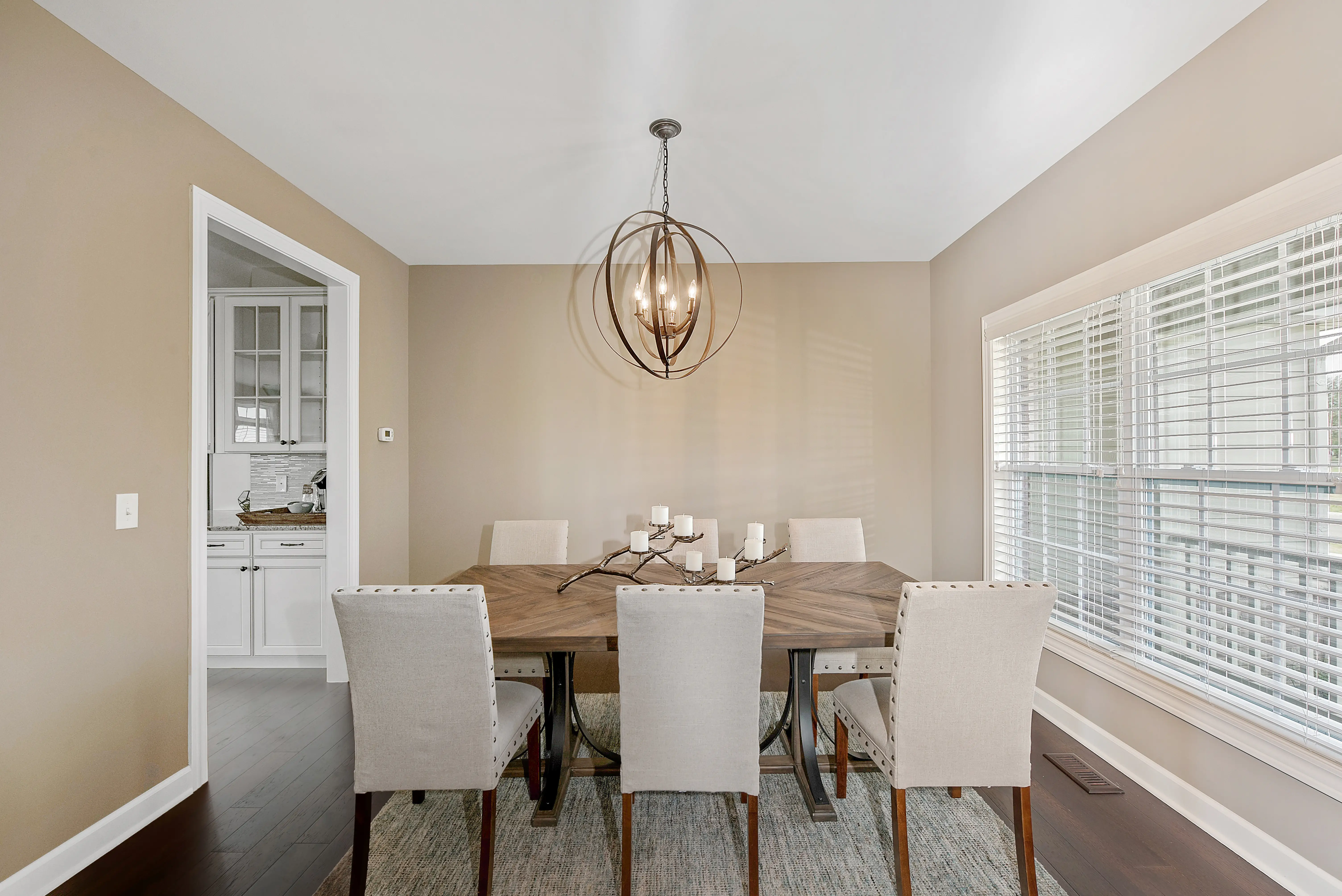 Dining room with beige walls, artsy light fixture, beige chairs
