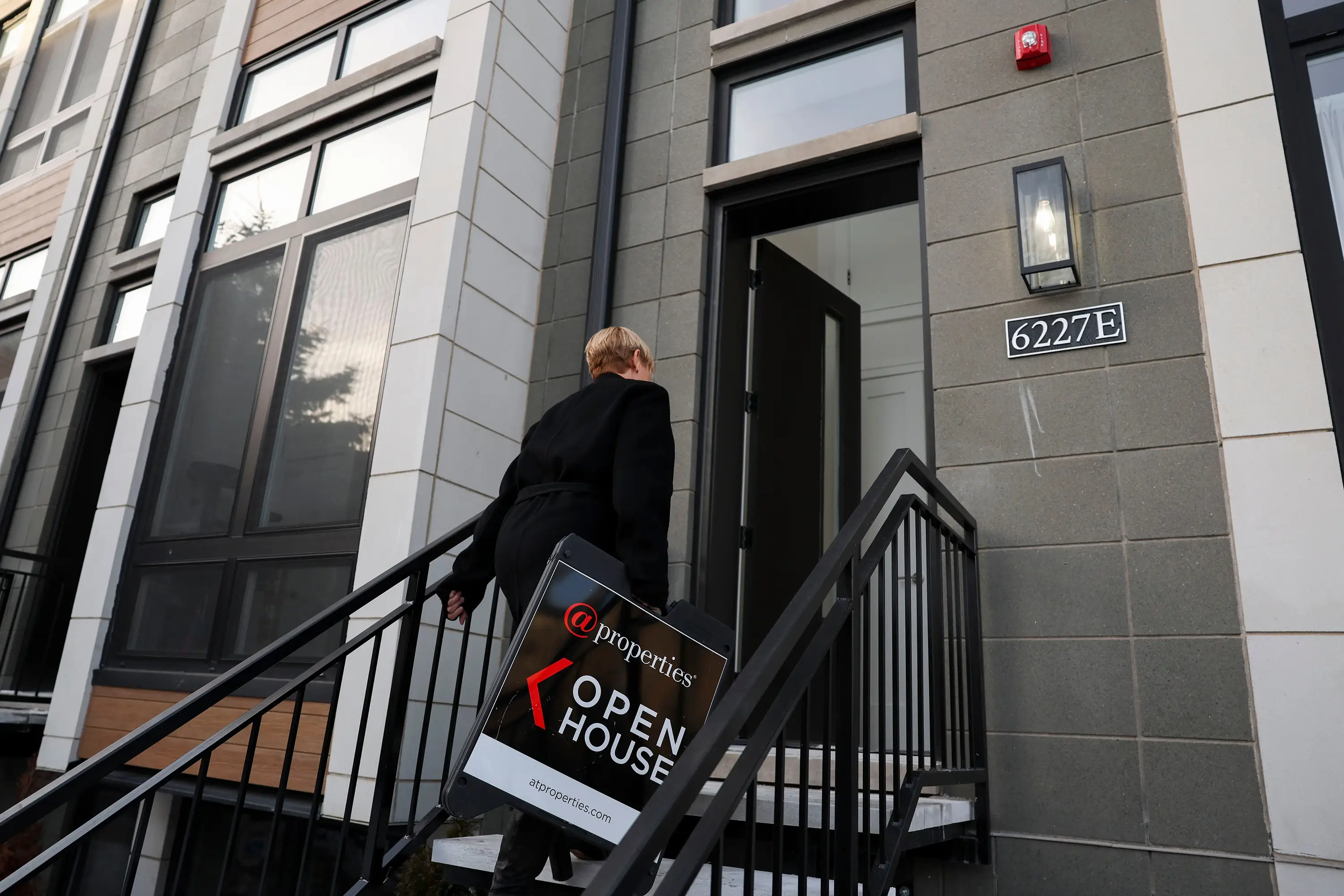 A real estate broker brings in a sign at the end of an open house for a modern, single-family row house in Chicago's Woodlawn neighborhood