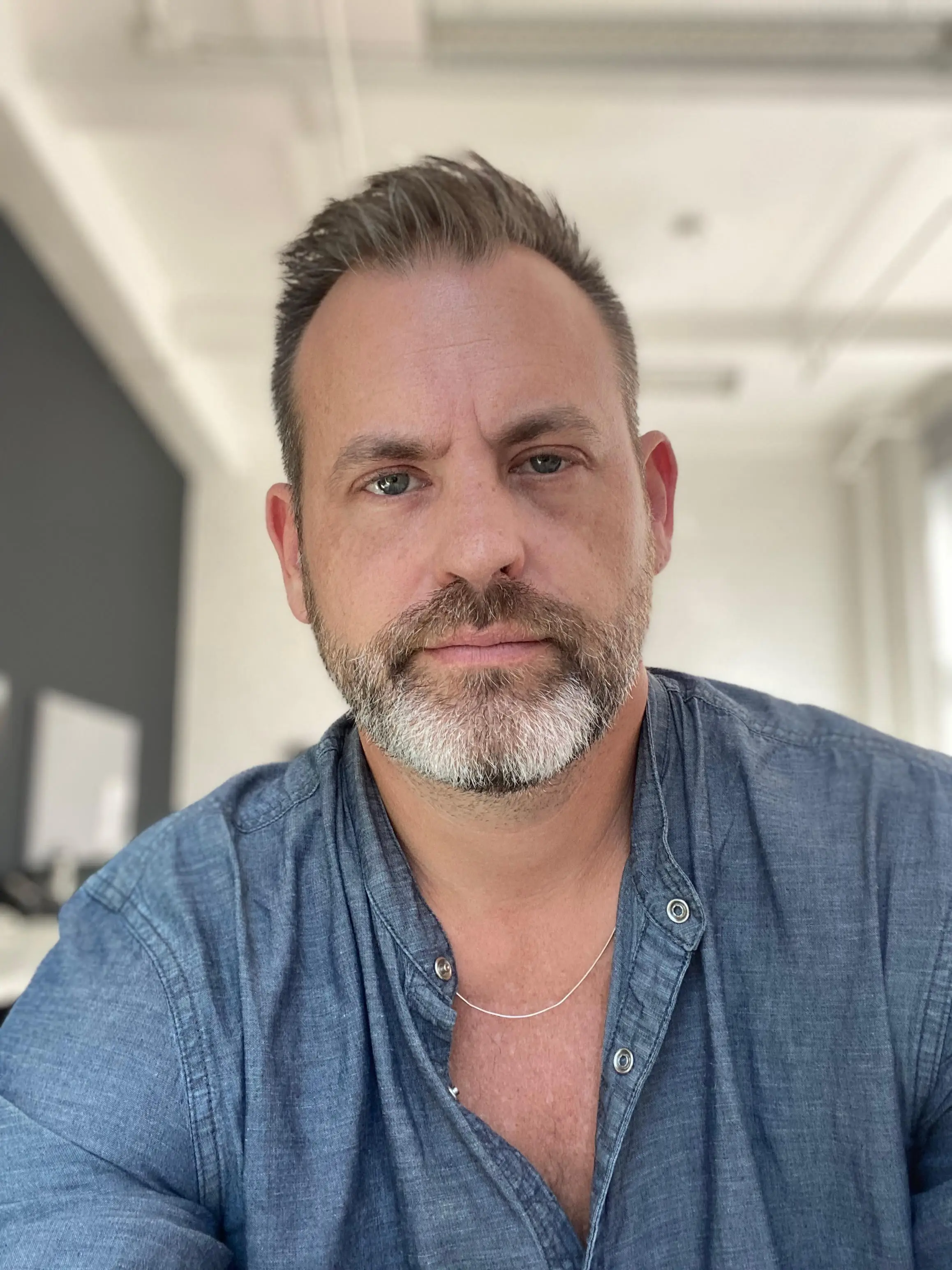 headshot of a man with a denim shirt and beard
