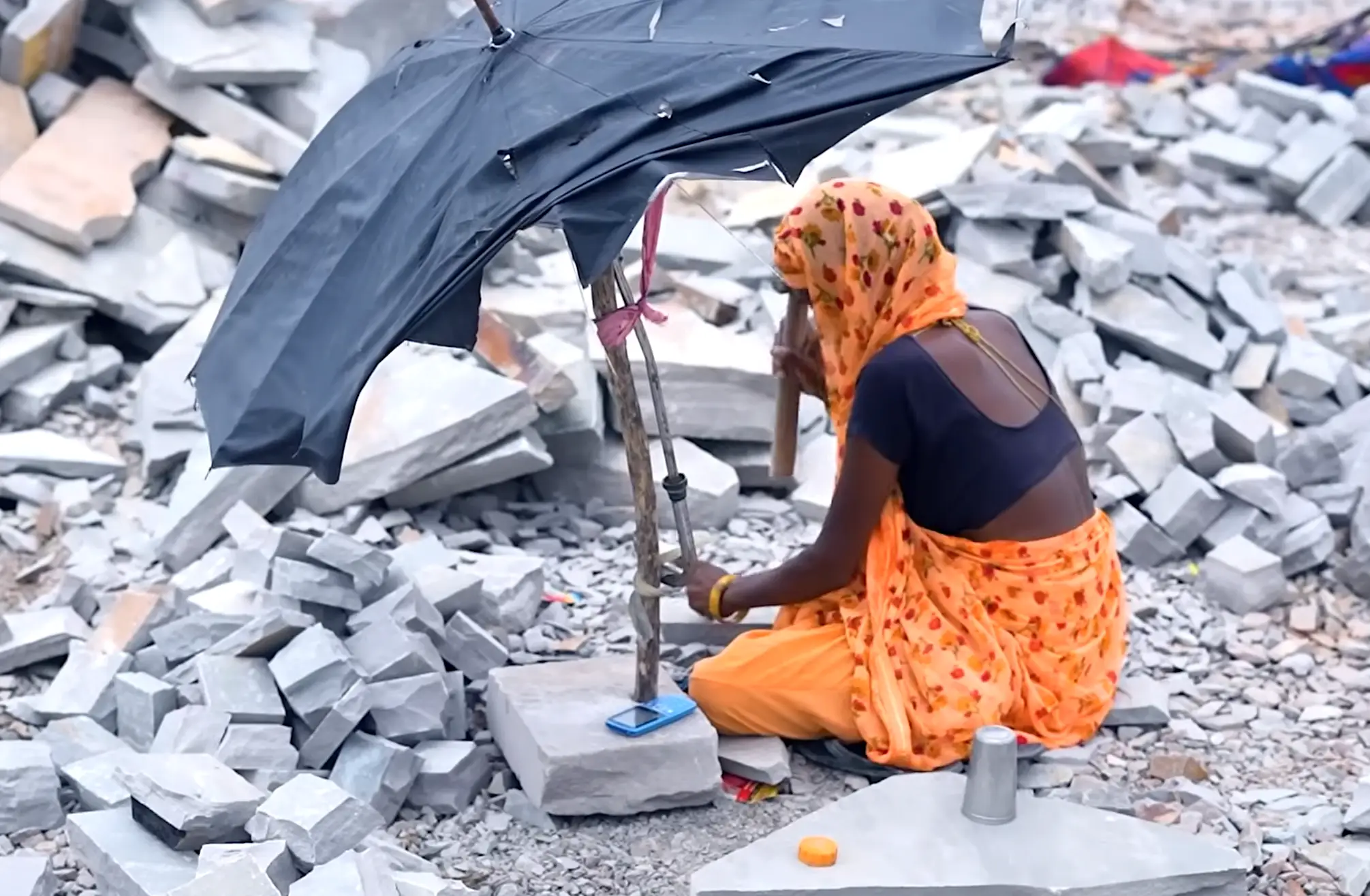 A woman breaking up stone into tiles.