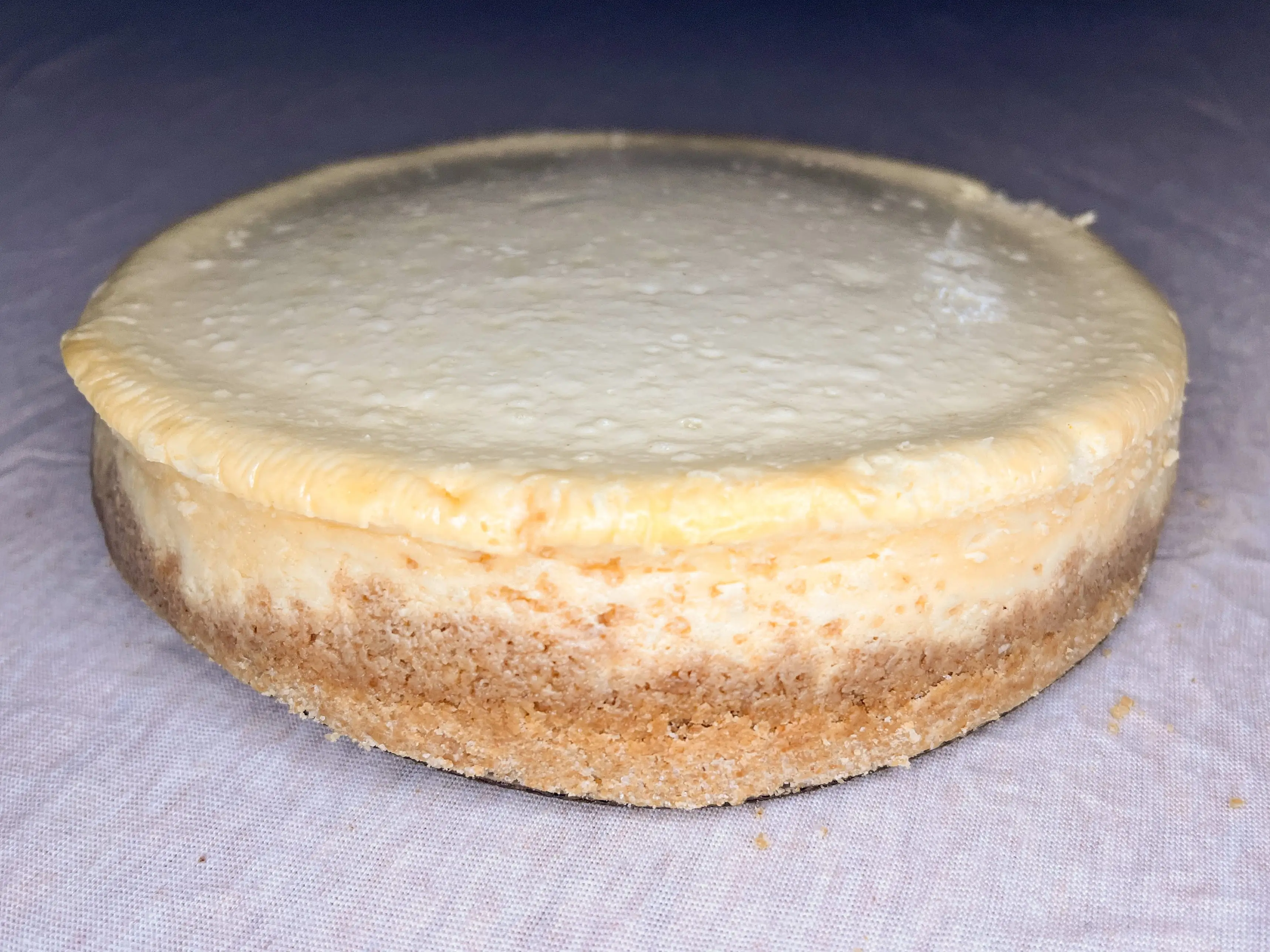 A whole cheesecake with a graham-cracker crust.