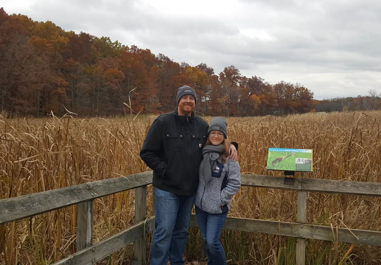 Two people posing in front of a park while on an autumn walk in Michigan.