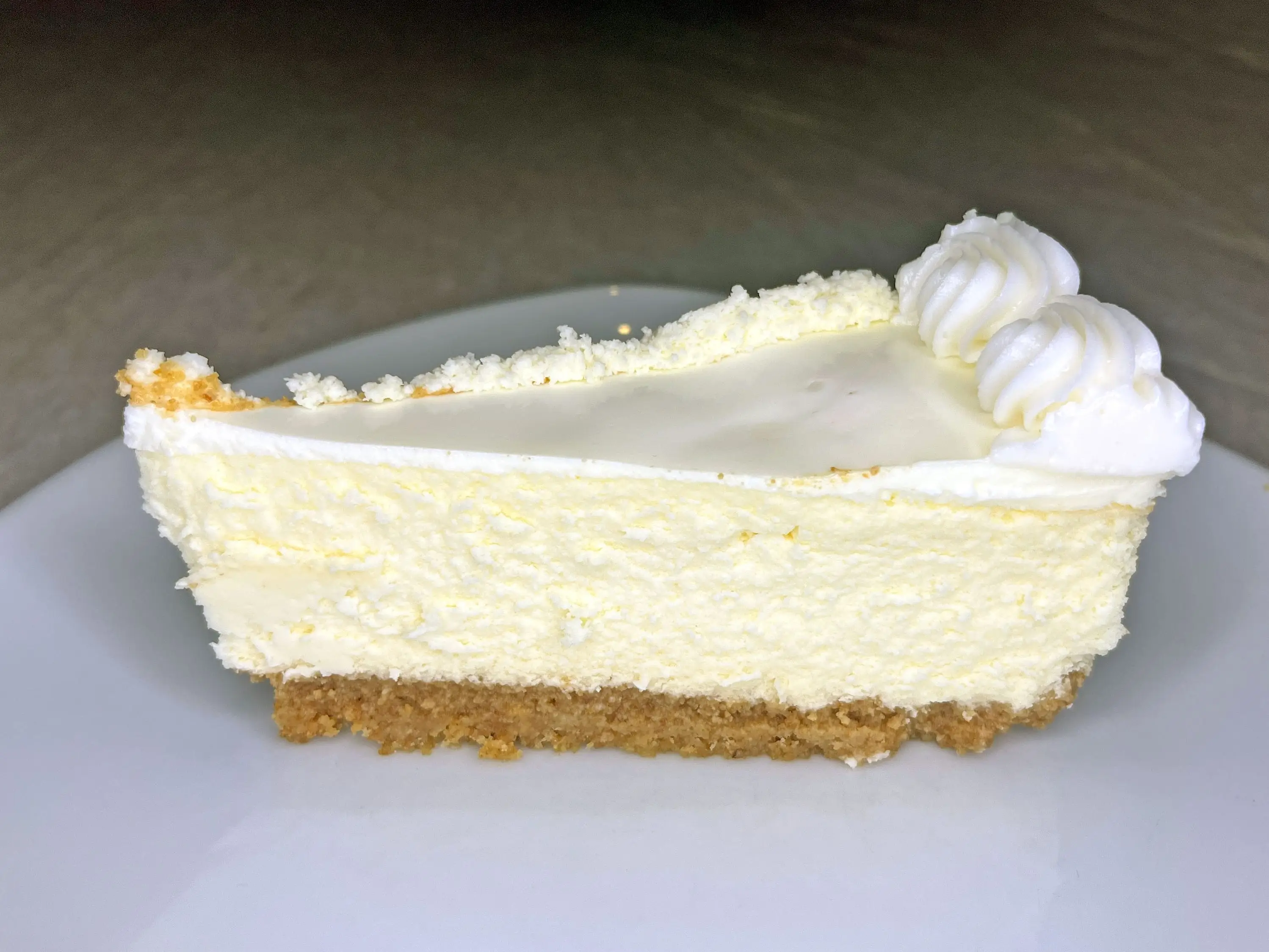 A slice of cheesecake that's topped with white frosting.