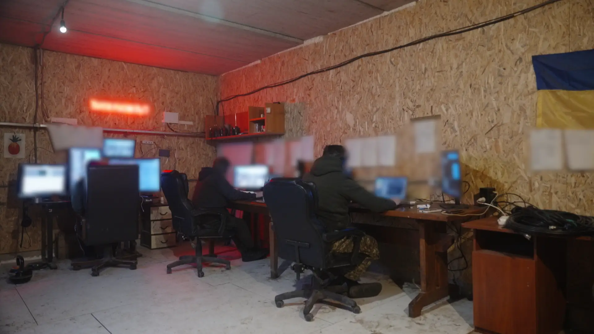 Three men sitting at brown desks in military fatigues