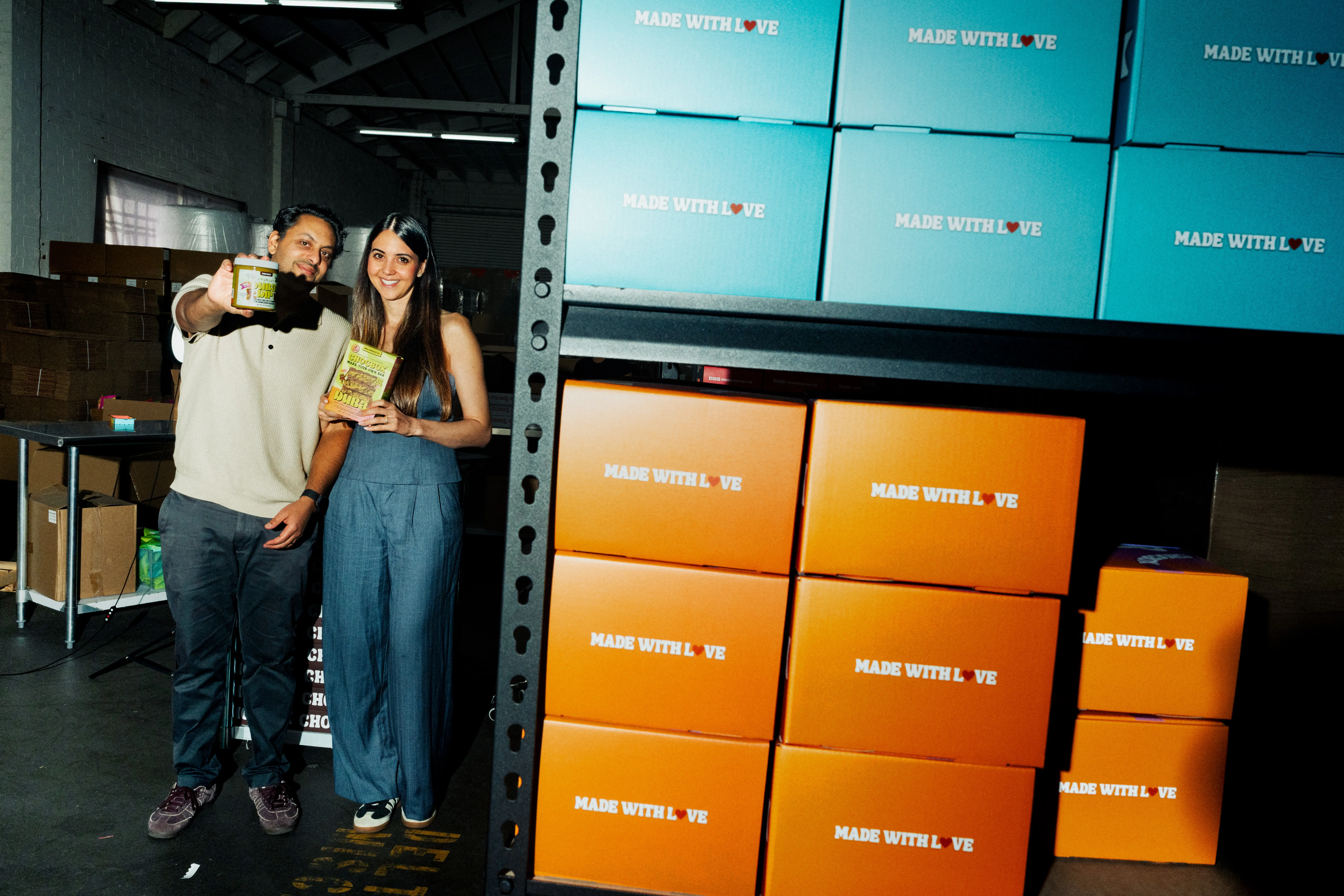 Portrait of Brittany and Kevin next to a shelf of their kits.