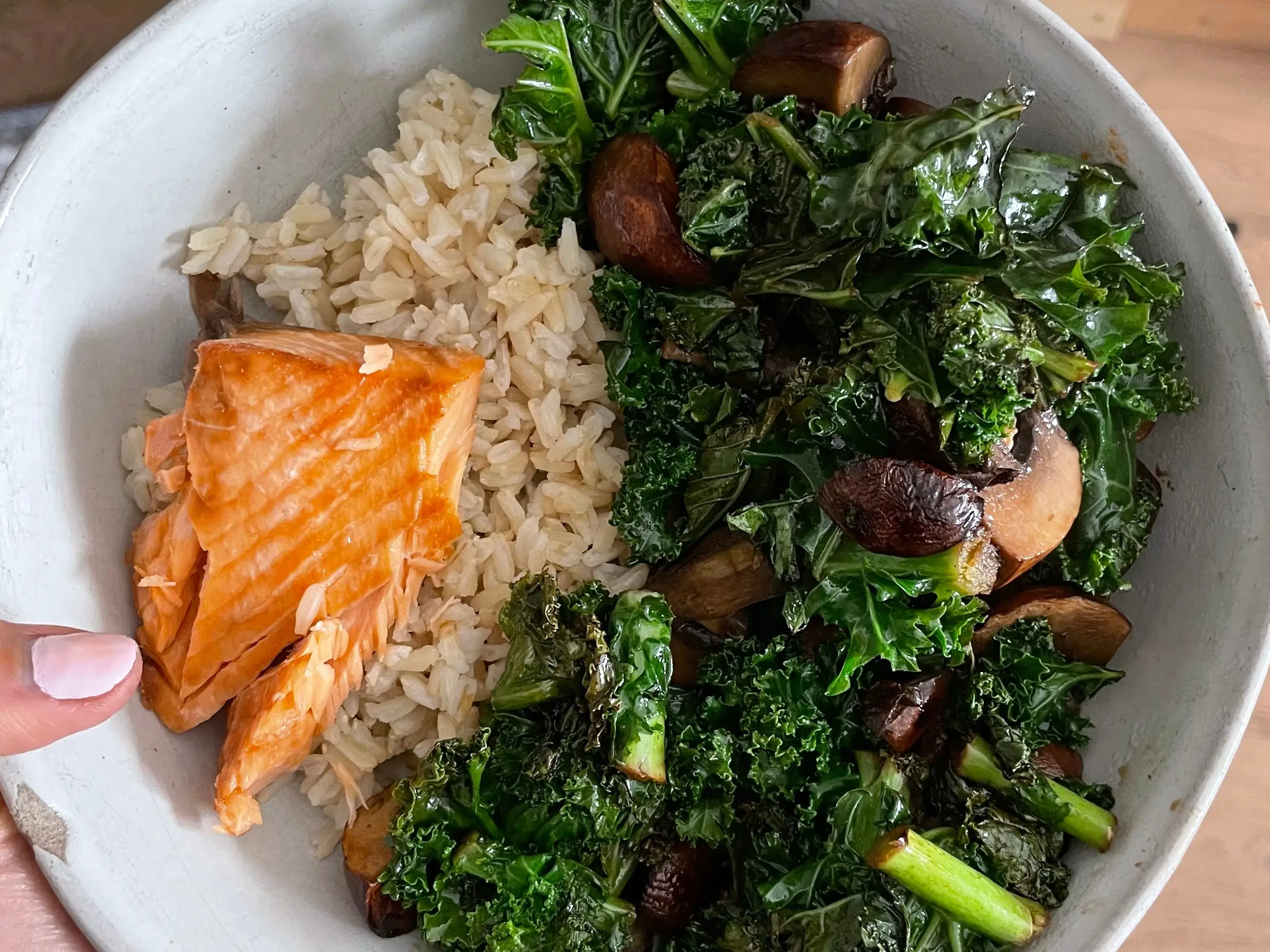 A bowl with salmon, kale and rice