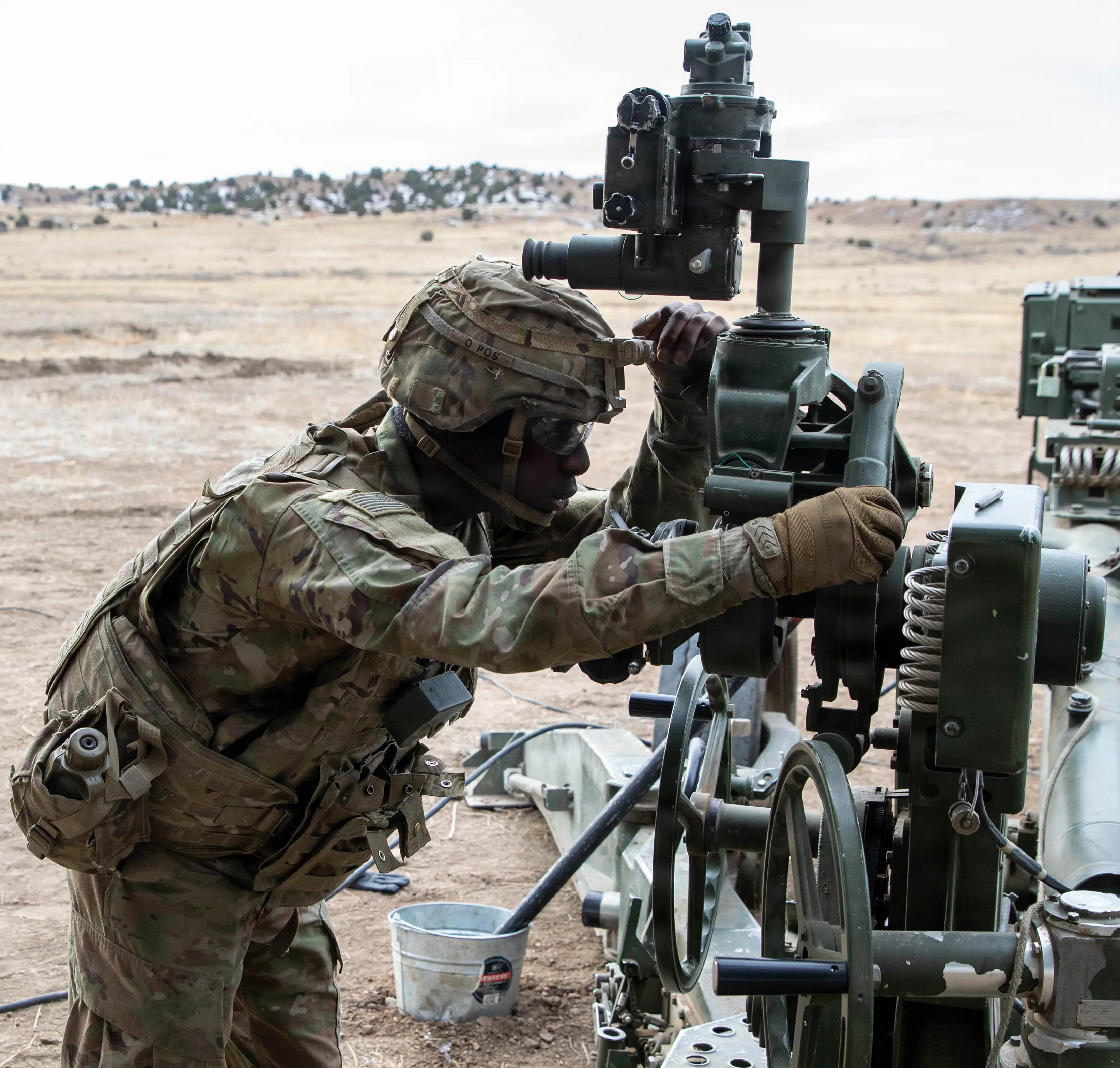 A man wearing camouflage works on a piece of machinery.