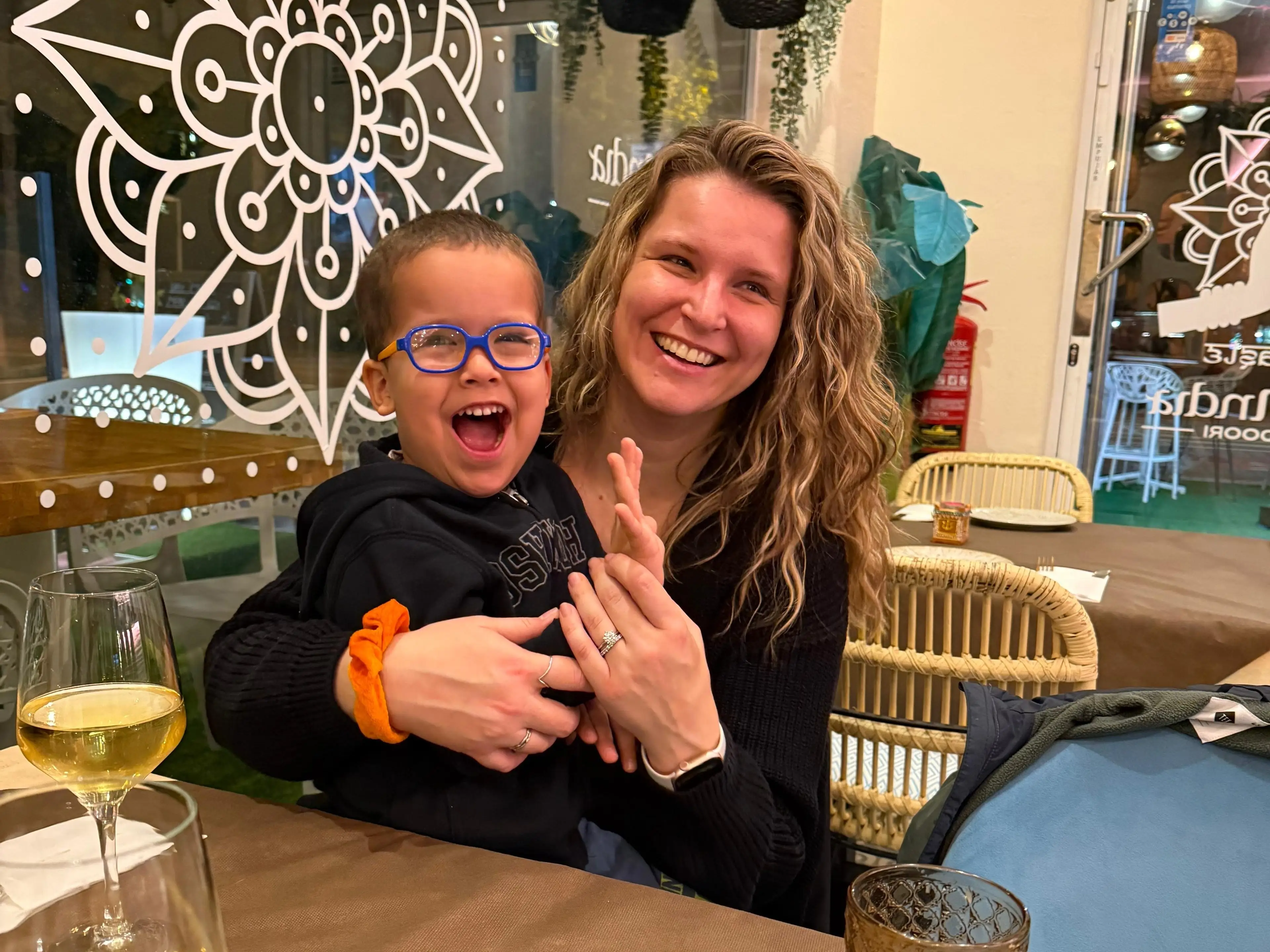 Izabela Oquendo and her son smiling at a table in a restaurant.