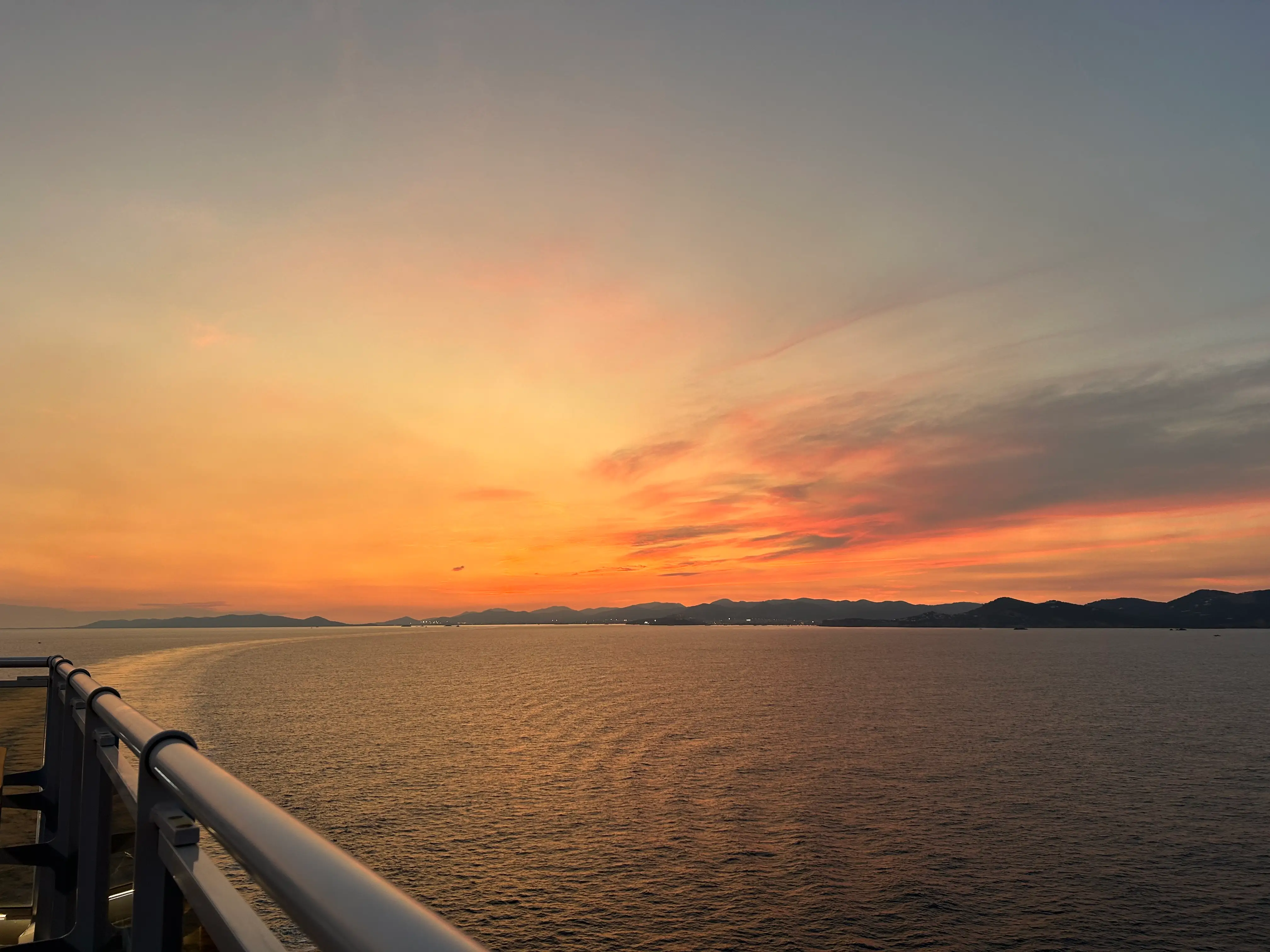 Sunset above ocean, view from railing of balcony on cruise