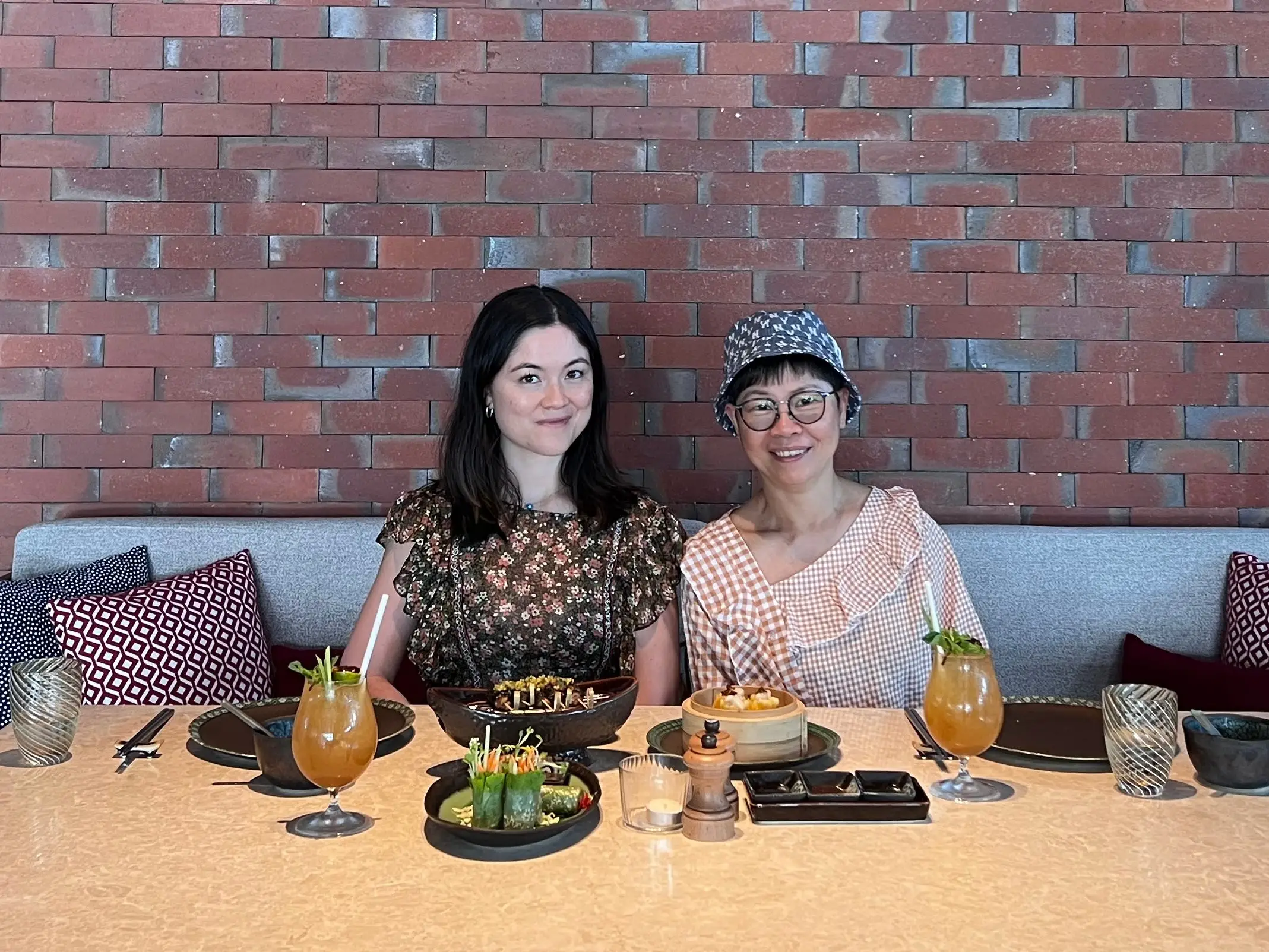 Mother and daughter sitting for Asian lunch with a brick wall in the background.