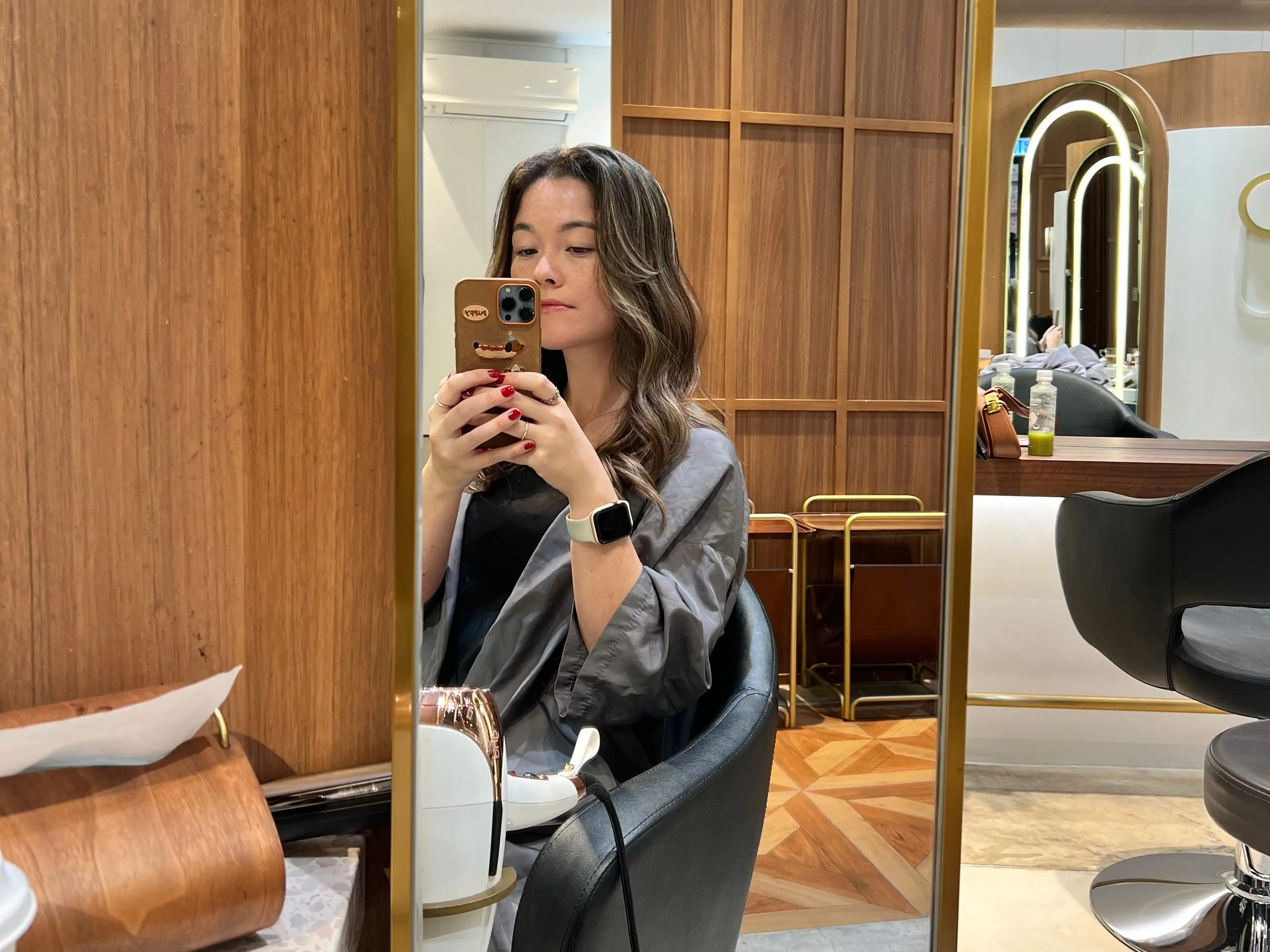 Woman taking a photo in the mirror at a hair salon.