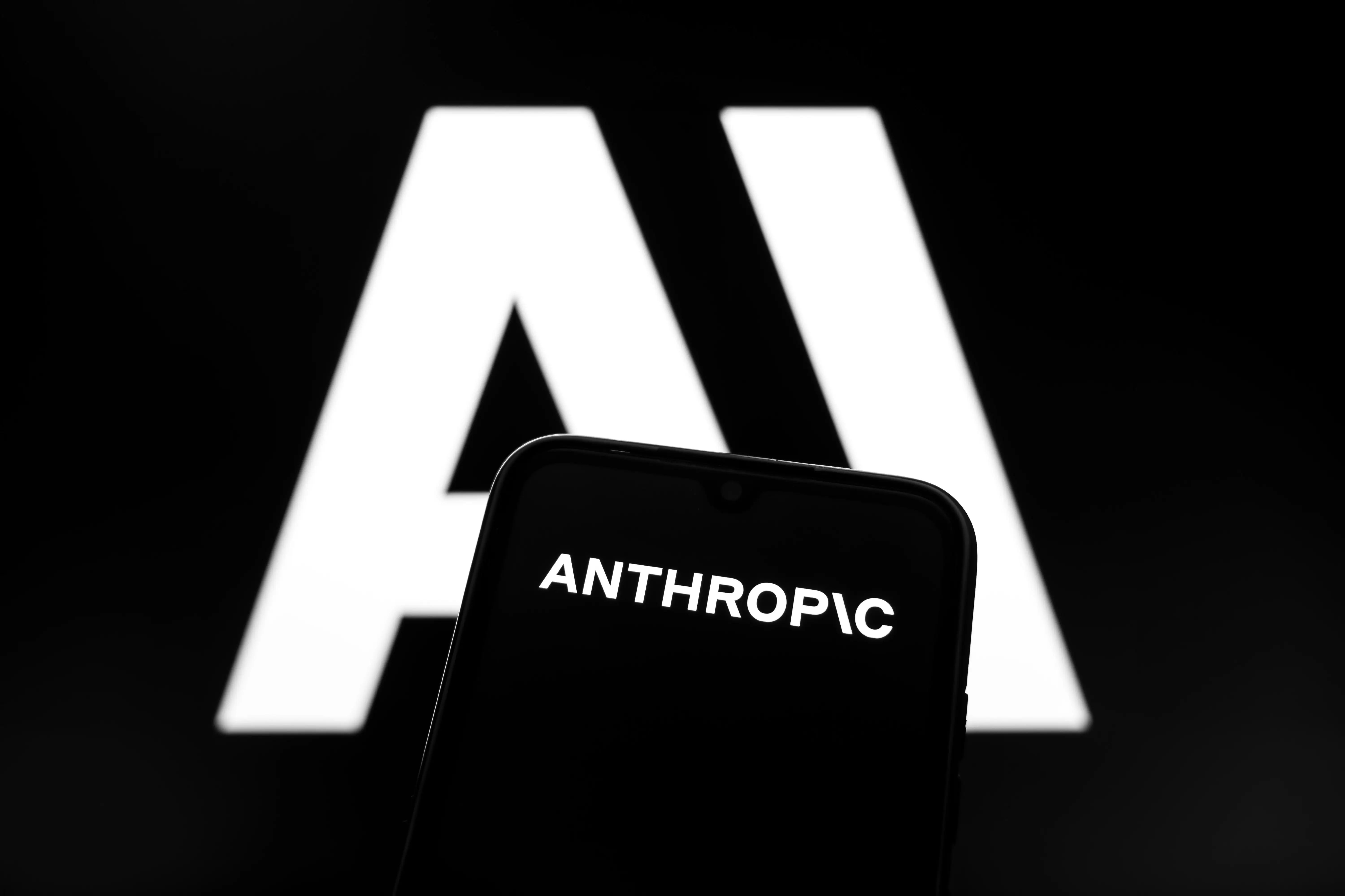 The Anthropic AI logo appears on a smartphone screen and as the background on a laptop computer screen in this photo illustration in Athens, Greece, on February 24, 2026.
