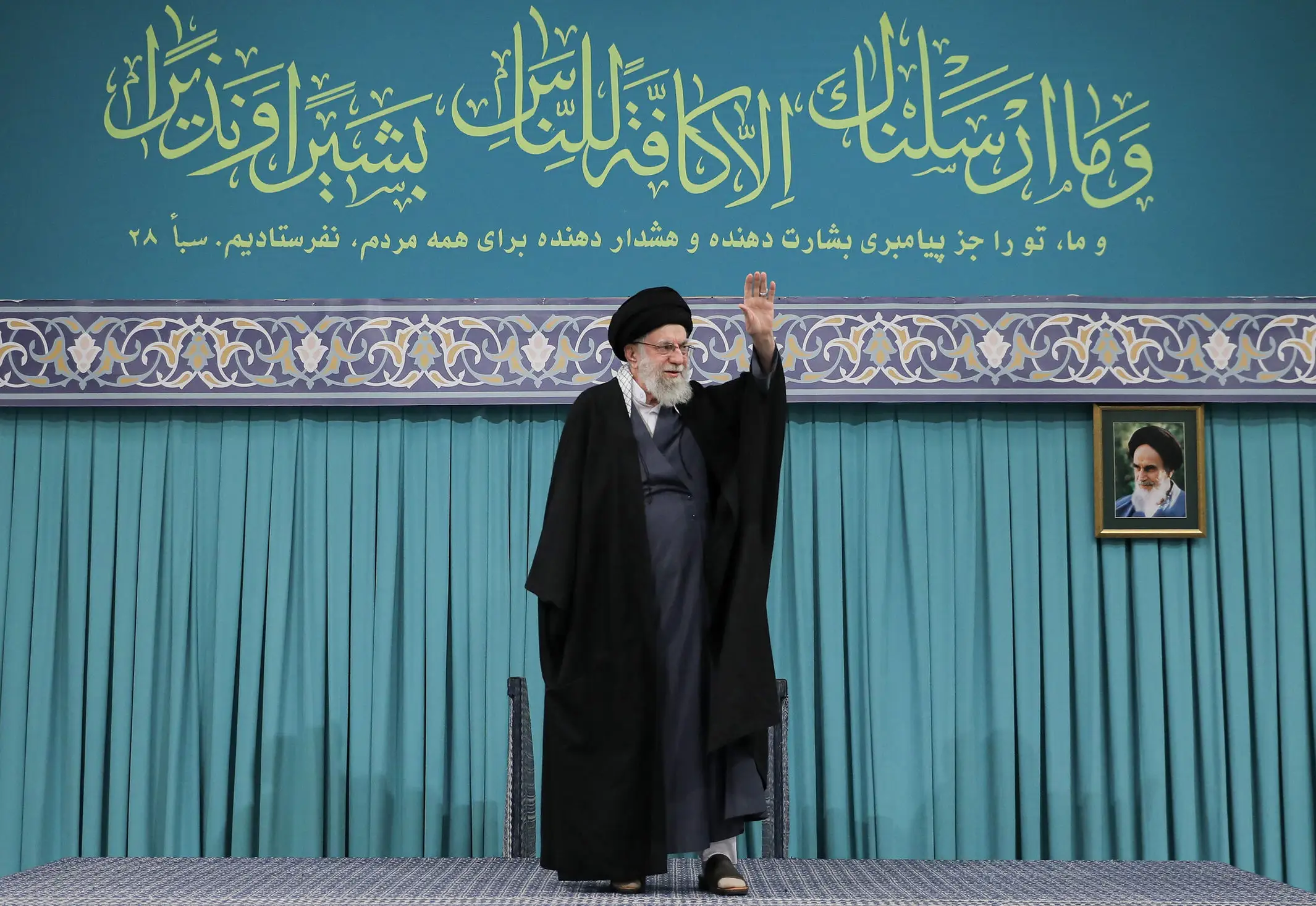 Iran's supreme leader, Ali Khamenei, waves to a crowd from a stage.