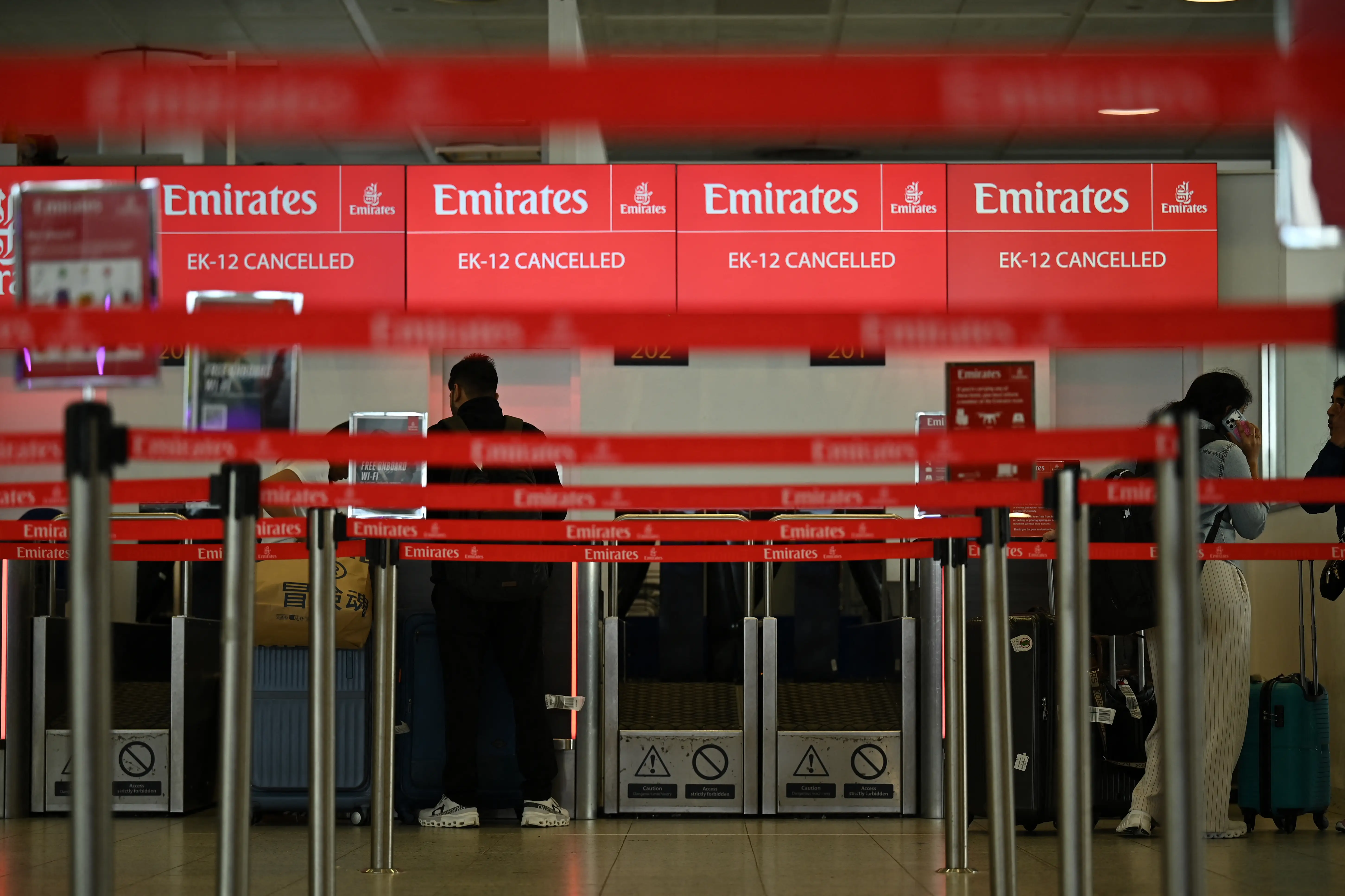 A check-in counter for Emirates at London Gatwick Airport shows cancelled flights on February 28.