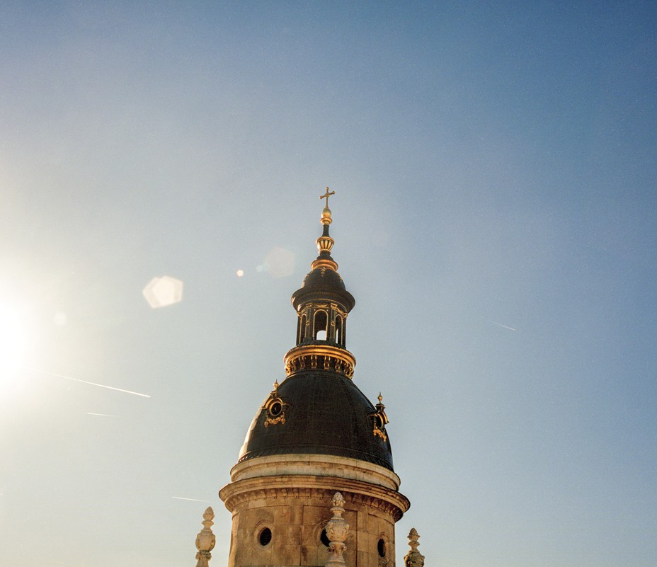 photo of top of spire of ornate church against bright blue sky