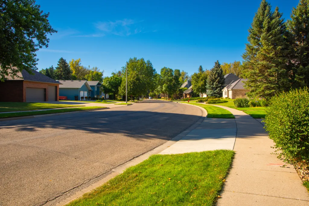 A modern residential neighborhood in Bismarck, North Dakota, featuring clean streets, green lawns, and houses with brick and siding exteriors.