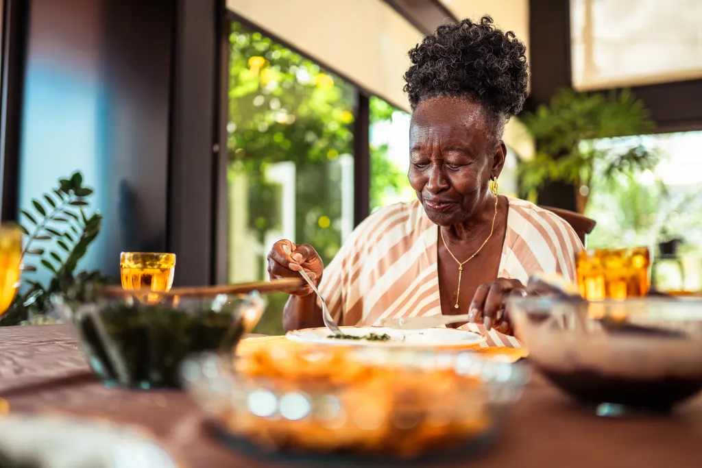 Contented senior African American woman enjoying a healthy meal at home.