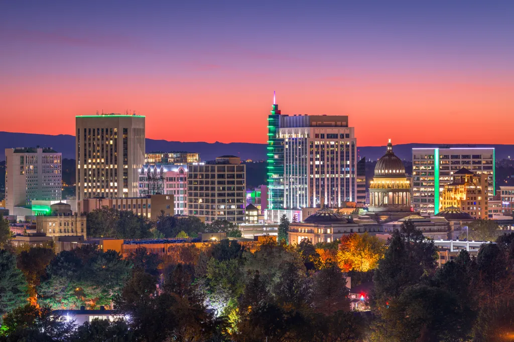 Downtown Boise, Idaho cityscape at twilight with illuminated buildings and a colorful sky.