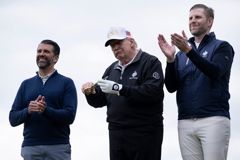 US President Donald Trump (C), flanked by his sons Eric Trump (R) and Donald Trump Jr. (L) cuts the ribbon on the first tee to officially open the Trump International Golf Links course in Balmedie, Aberdeenshire, north east Scotland on July 29, 2025. (Photo by Brendan Smialowski / AFP) (Photo by BRENDAN SMIALOWSKI/AFP via Getty Images)