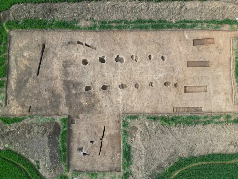 Aerial view of an archaeological excavation site with rectangular and circular trenches.