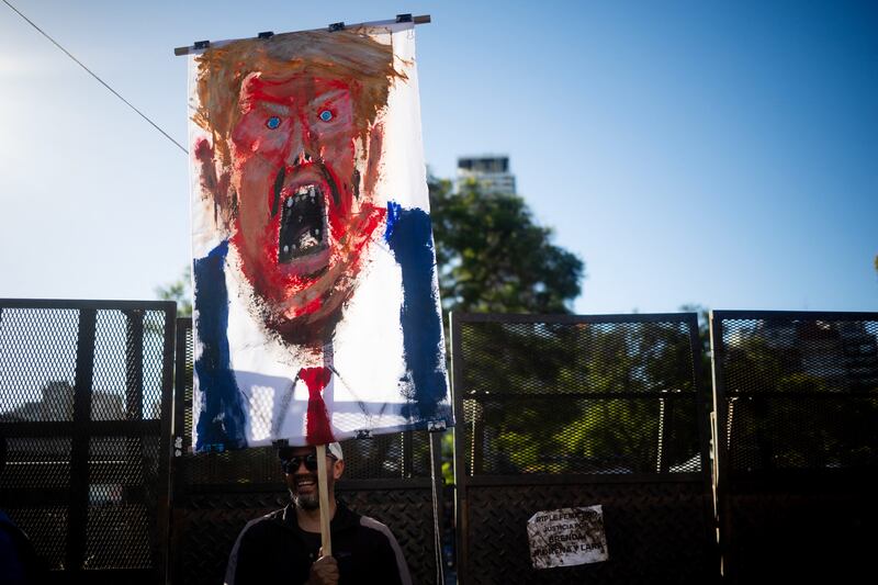 A man holds a painting depicting United States President Donald Trump during a protest against the US intervention in Venezuela, in Buenos Aires on January 5, 2026.