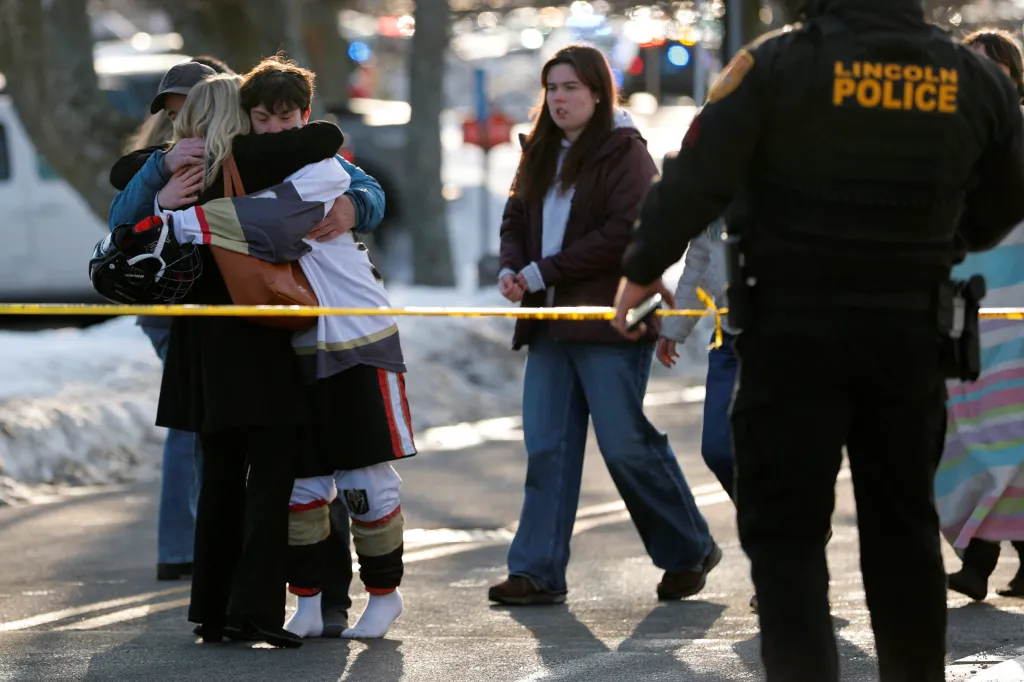 A youth wearing hockey gear is embraced outside the Dennis M Lynch Arena, an indoor ice skating rink, after a shooting in Pawtucket, Rhode Island, U.S., February 16, 2026.