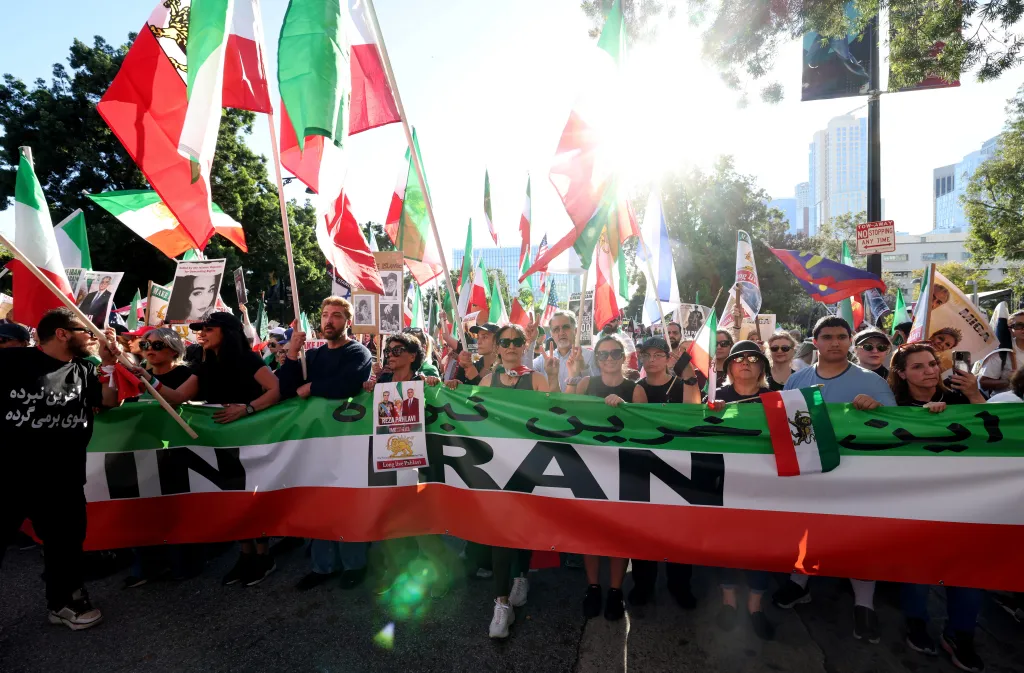 People marching in Los Angeles with Iranian flags and a large banner that reads 