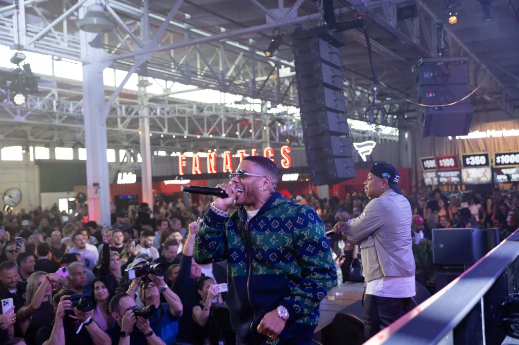 Rapper Nelly performing on stage with a large crowd in front of him.