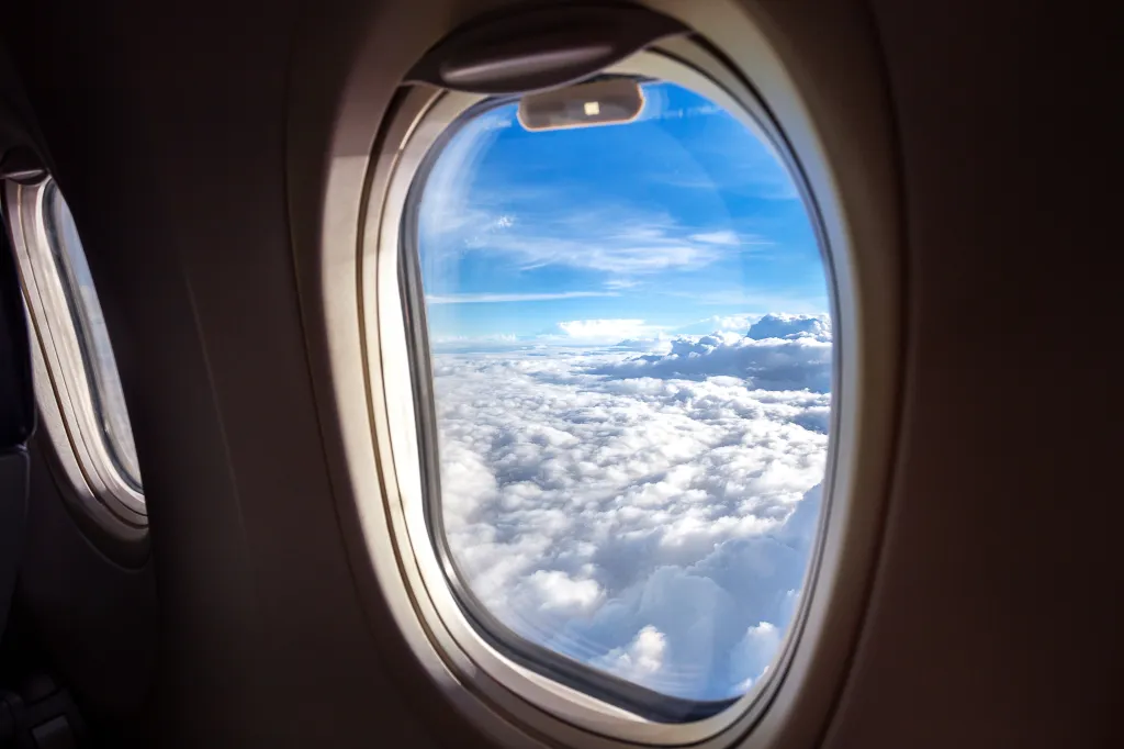 View of clouds and blue sky from an airplane window.