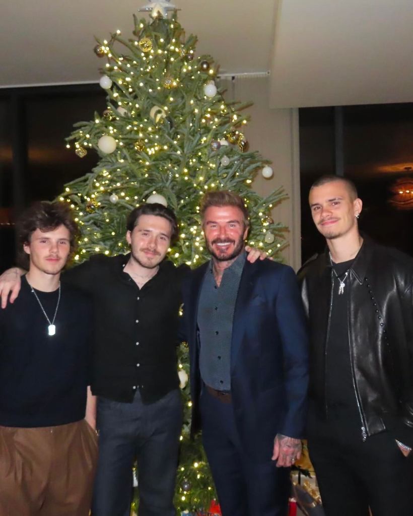 Cruz, Brooklyn, David, and Romeo Beckham in front of a Christmas tree.
