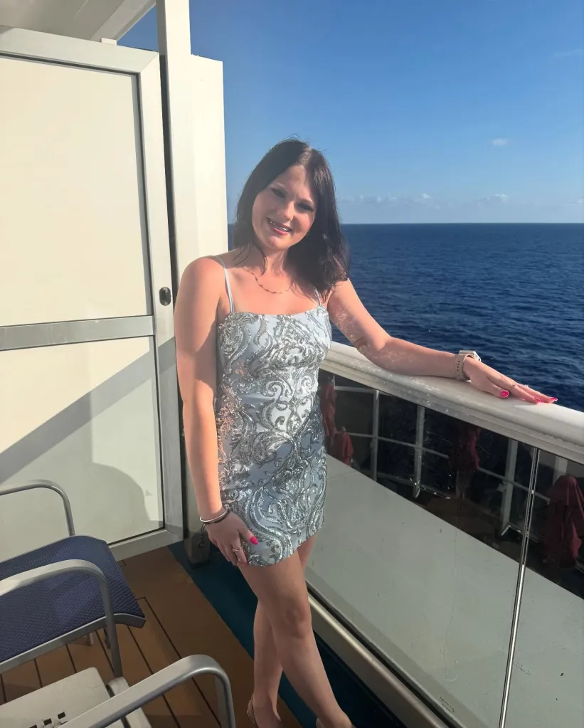 Anna Kepner wearing a light blue dress with silver sequins on a cruise ship balcony.