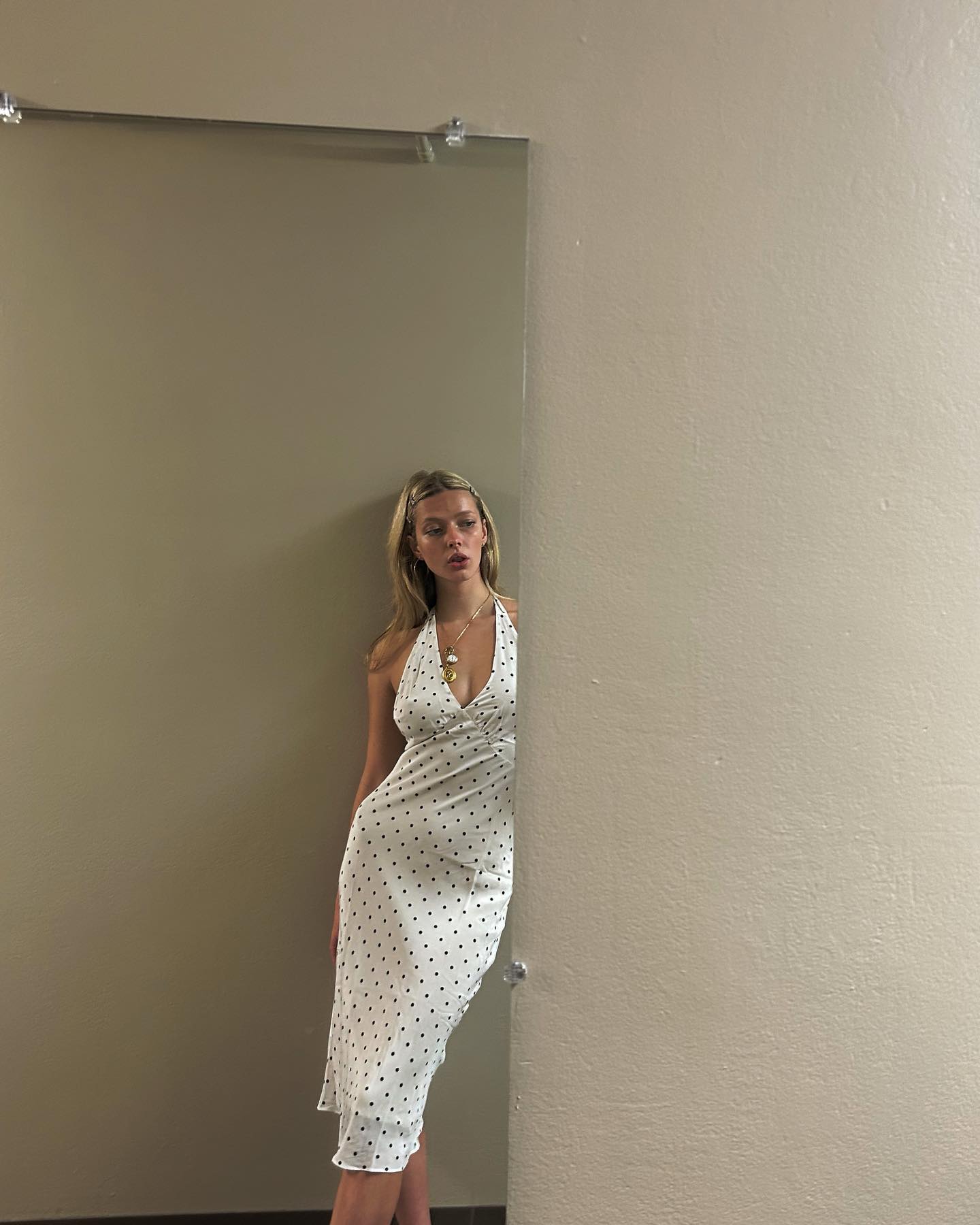 Apple Martin in a white polka dot dress looking away from the camera.