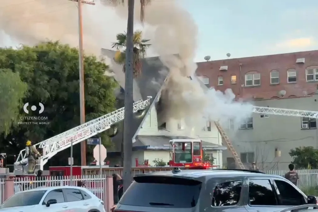 Firefighters battling a house fire in Arlington Heights, Los Angeles, with smoke billowing from the building.
