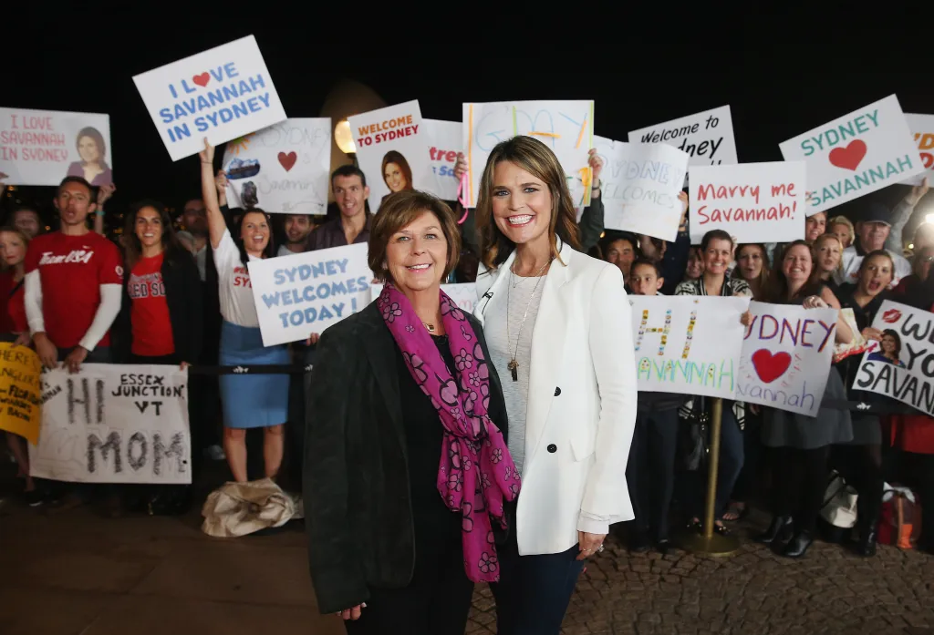 Savannah Guthrie and her mother Nancy Guthrie posing for a photo, surrounded by fans holding signs.