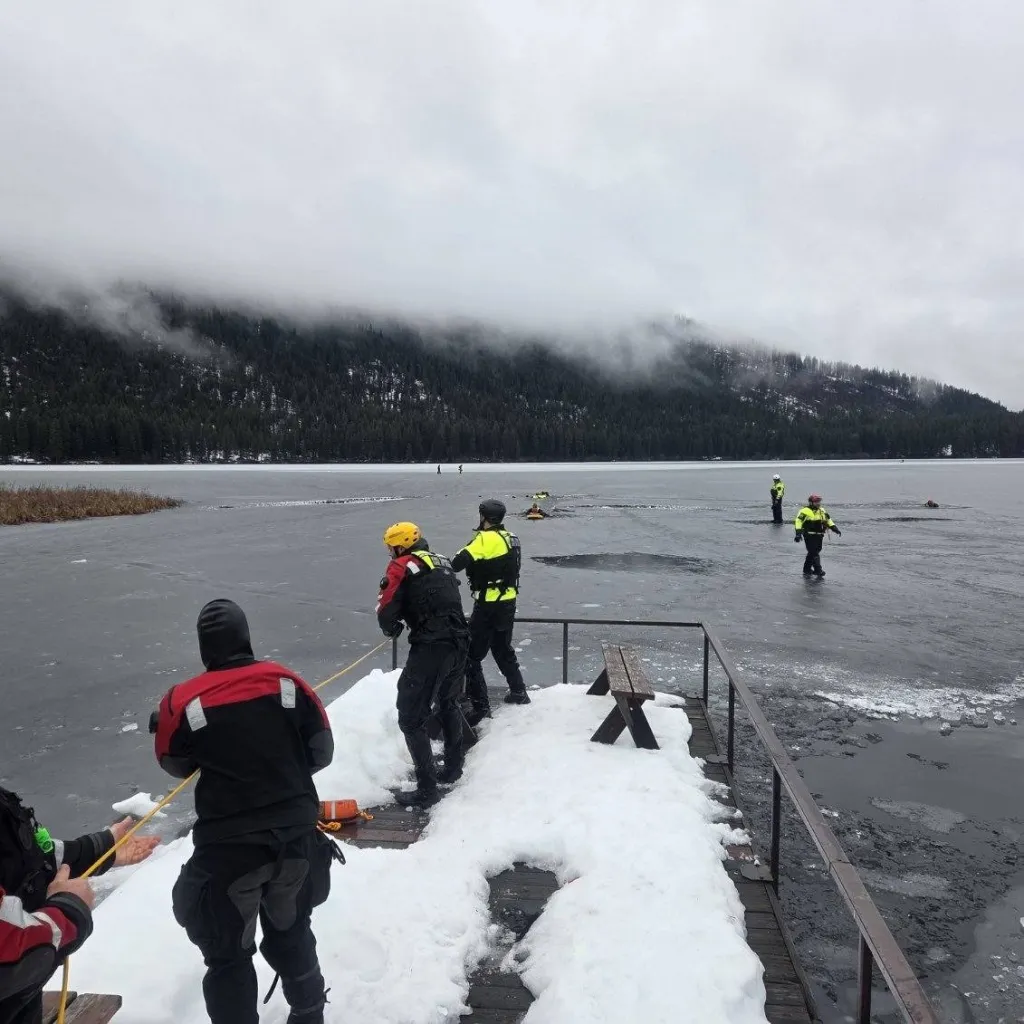Rescue personnel conducting ice rescue training on a partially frozen lake.