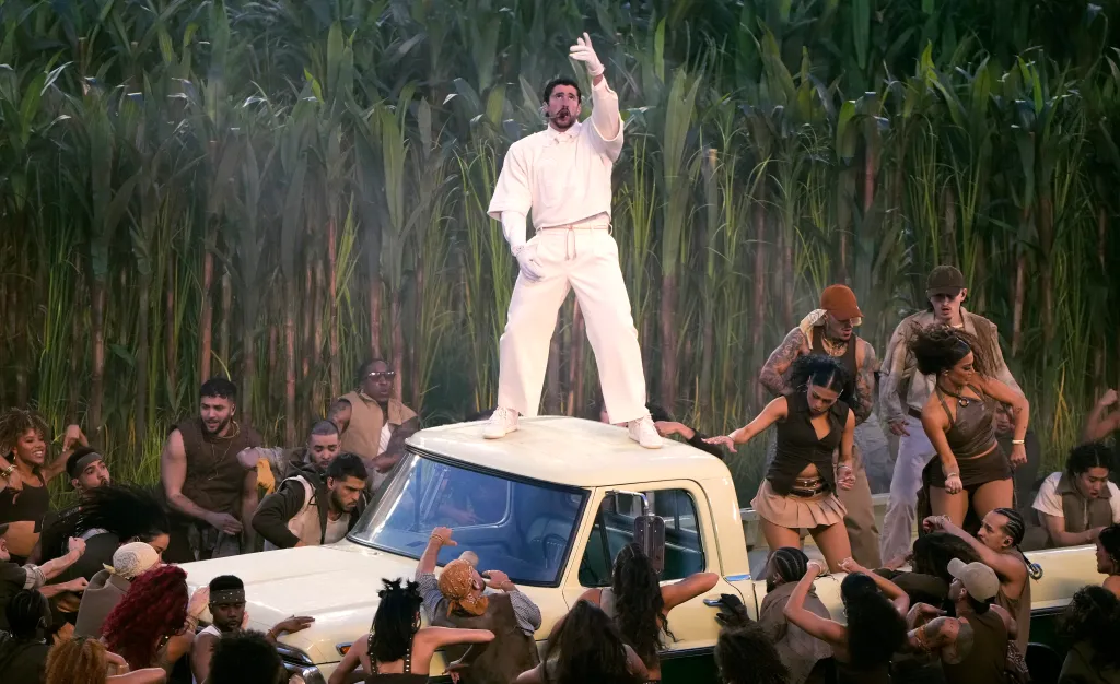 Bad Bunny performing on top of a pickup truck with dancers surrounding him on stage at the Apple Music Super Bowl LX Halftime Show.