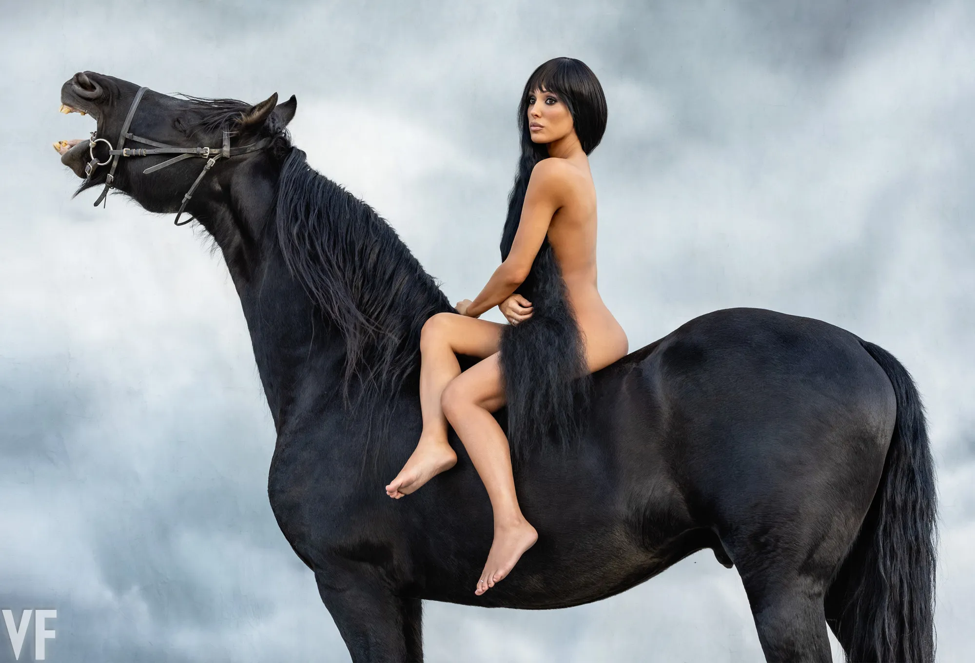 Bianca Censori, wife of Kanye West, sits nude on a black horse that rears up with its mouth open.