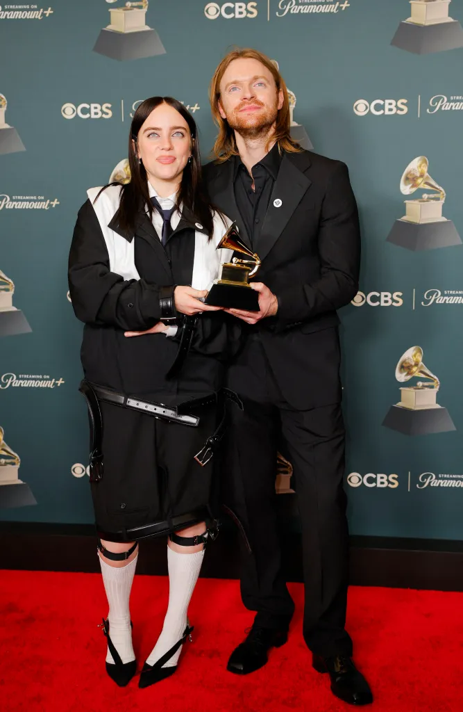 Billie Eilish and Finneas wearing ICE Out pins pose with the award for Song of the Year for 