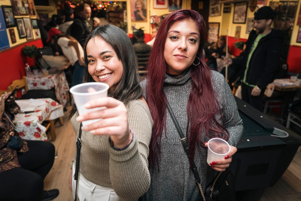 Brenda Briones and Jaccia Sepúlveda posing with drinks in a room with a pool table.